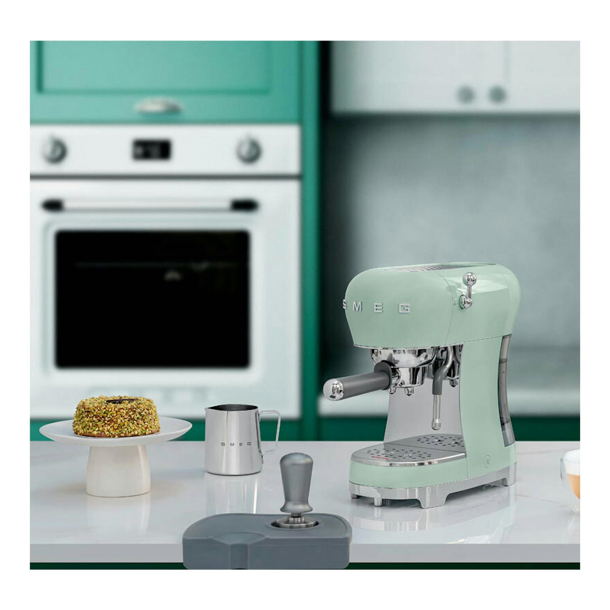 Cafetera expreso Smeg ECF02PGEU verde menta, vista frontal lateral sobre encimera en una cocina.