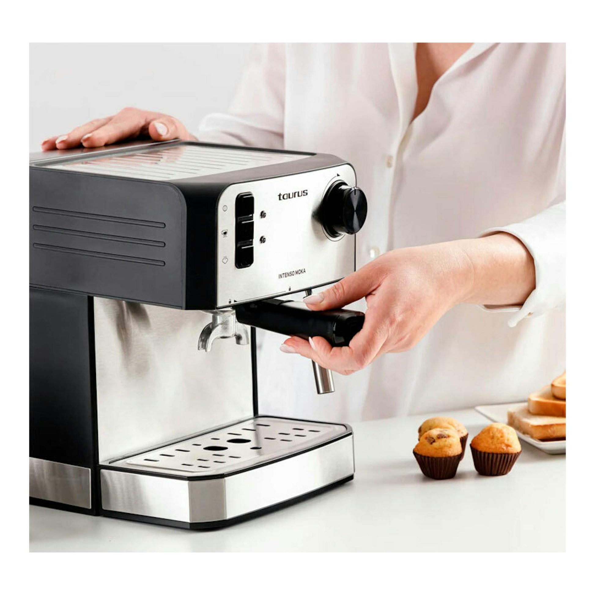 Cafetera espresso Taurus Intenso Moka negra y plateada, vista frontal inclinada, con una mano sujetando el portafiltro.