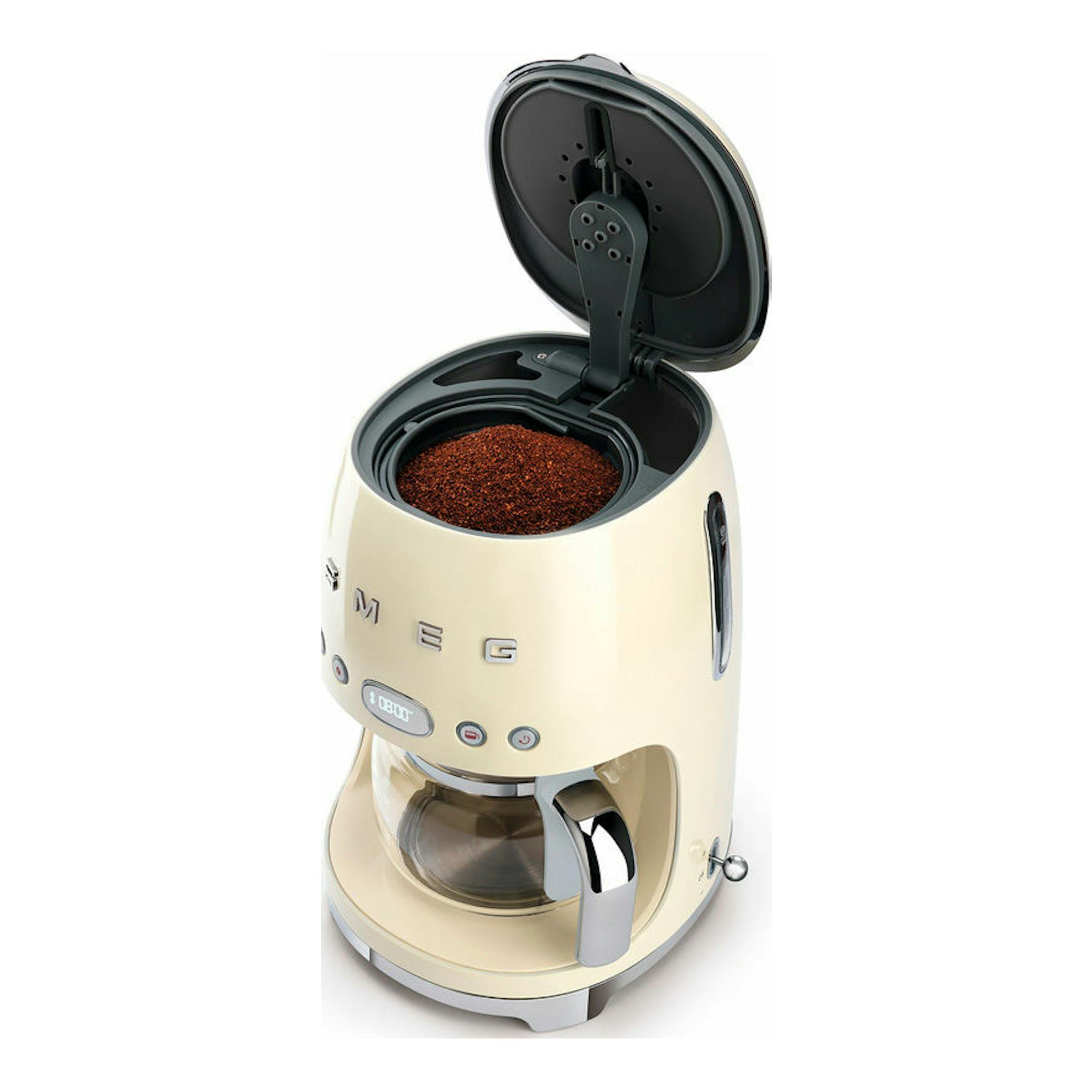 Cafetera de goteo Smeg DCF02CREU crema, vista frontal en 3/4 con tapa superior abierta y depósito visible.