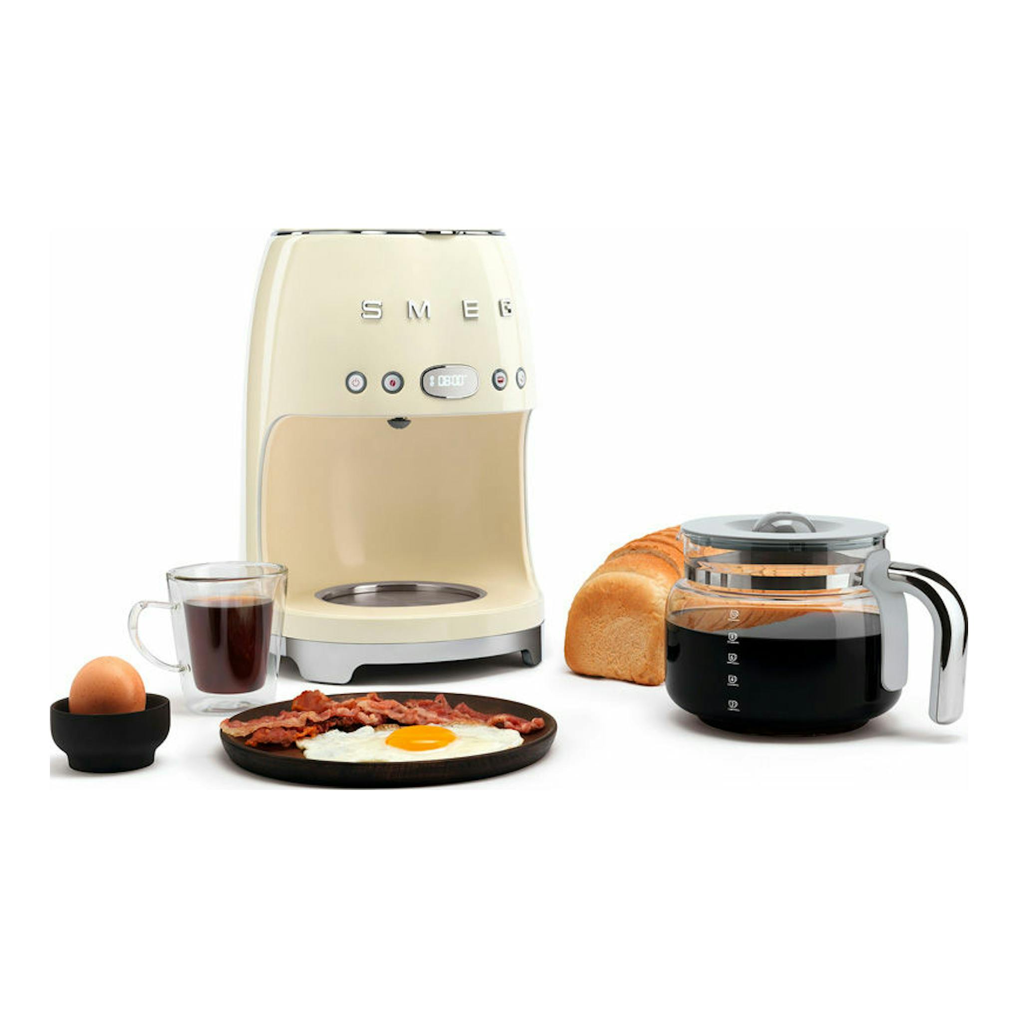 Cafetera de goteo Smeg DCF02CREU crema, vista frontal, con jarra, taza y pan.