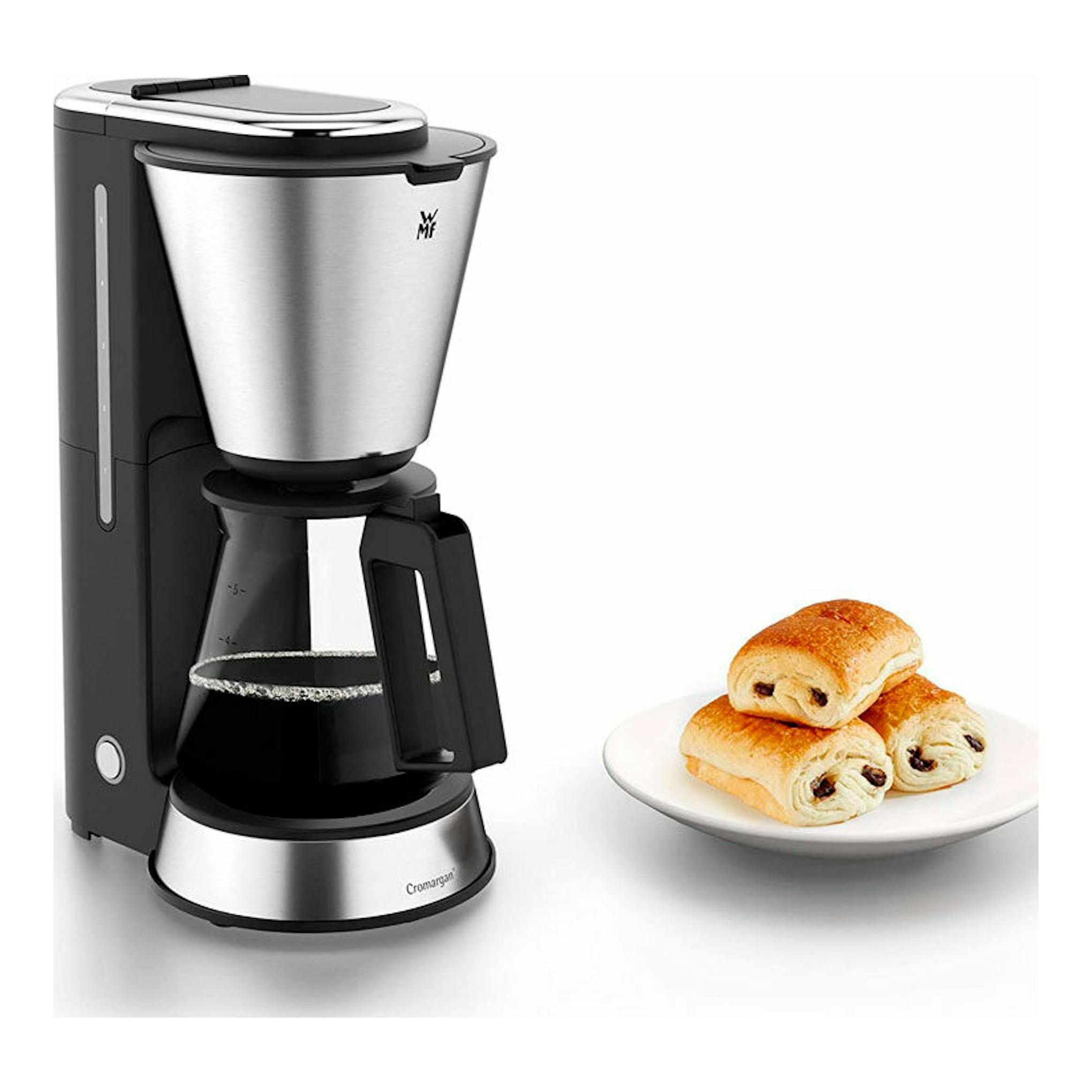 Cafetera de goteo WMF Aroma, negro y acero inoxidable, vista frontal con jarra de cristal y un plato con bollos.
