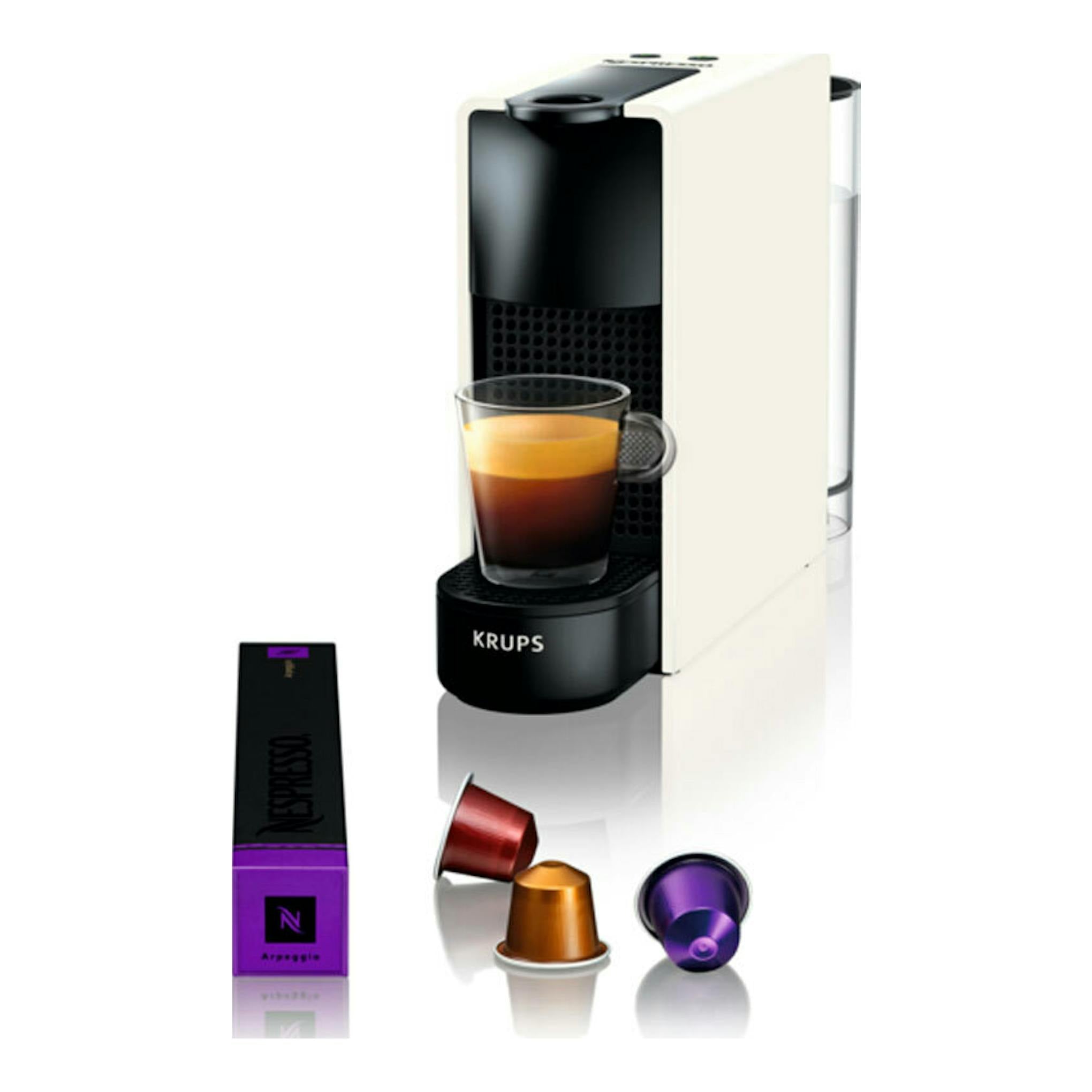 Krups Nespresso XN1101RD blanca y negra, vista frontal en tres cuartos, con taza de café y cápsulas.