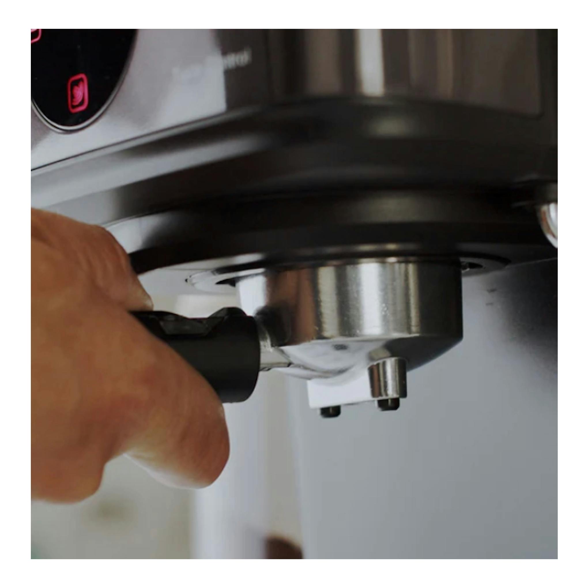 Solac Taste Control, cafetera espresso en primer plano, mano colocando el portafiltro bajo el grupo, negro y acero.