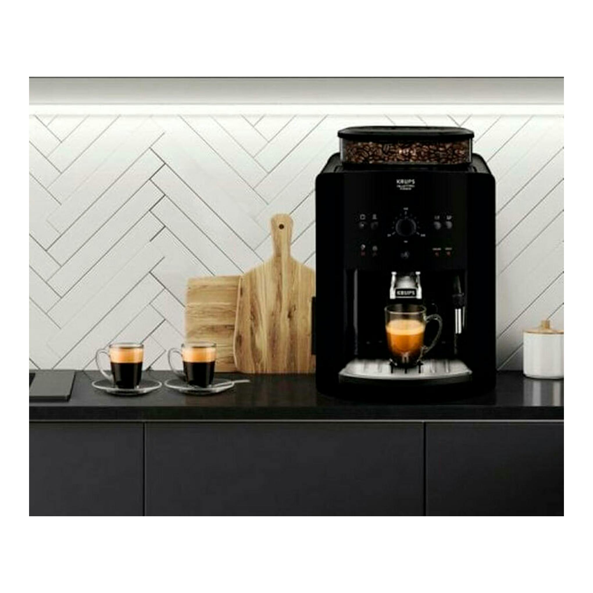 Cafetera superautomática Krups EA811010 negra, vista frontal, sobre encimera con una taza de café.