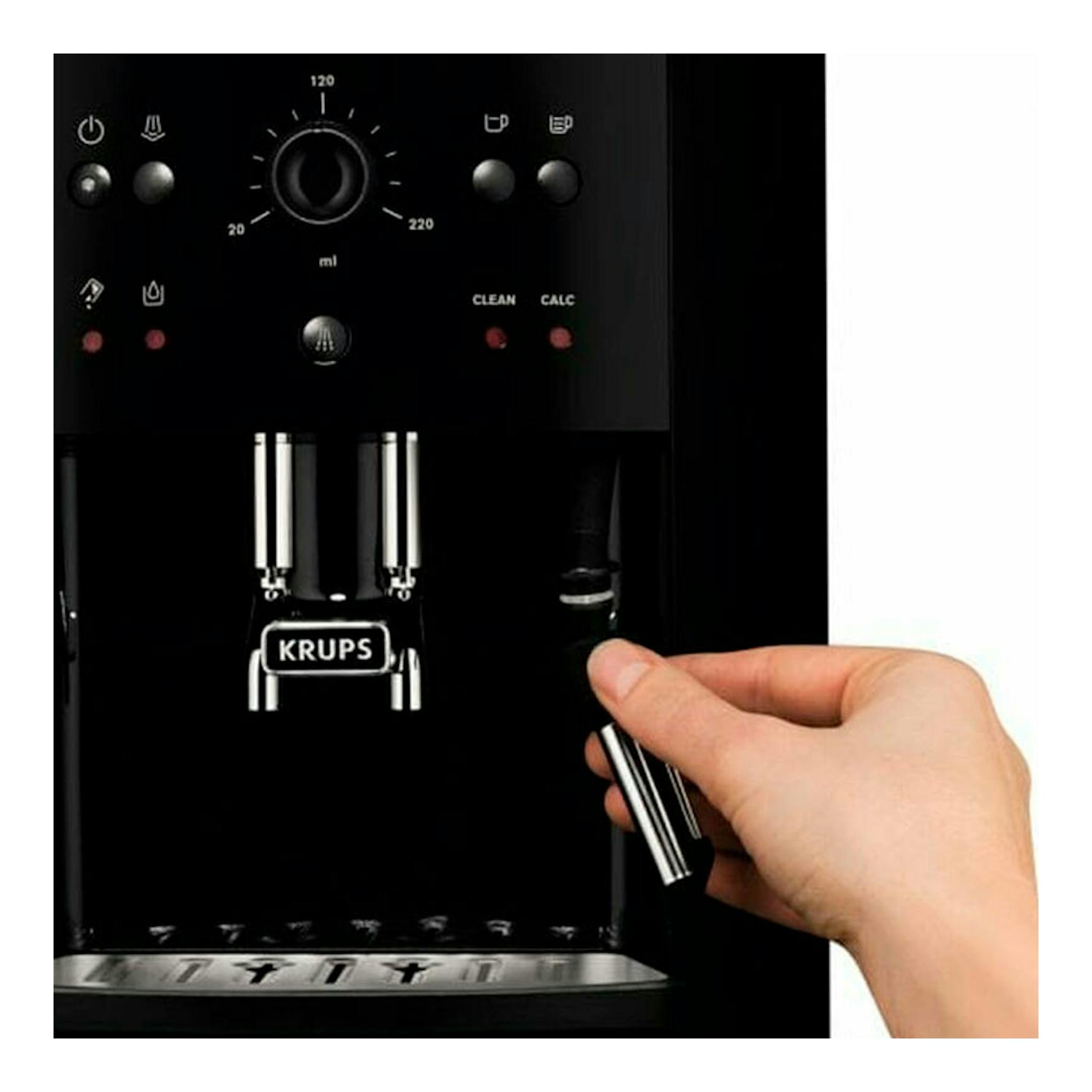 Máquina de café Krups EA811010 negra, vista frontal, con una mano sujetando la lanza de vapor.