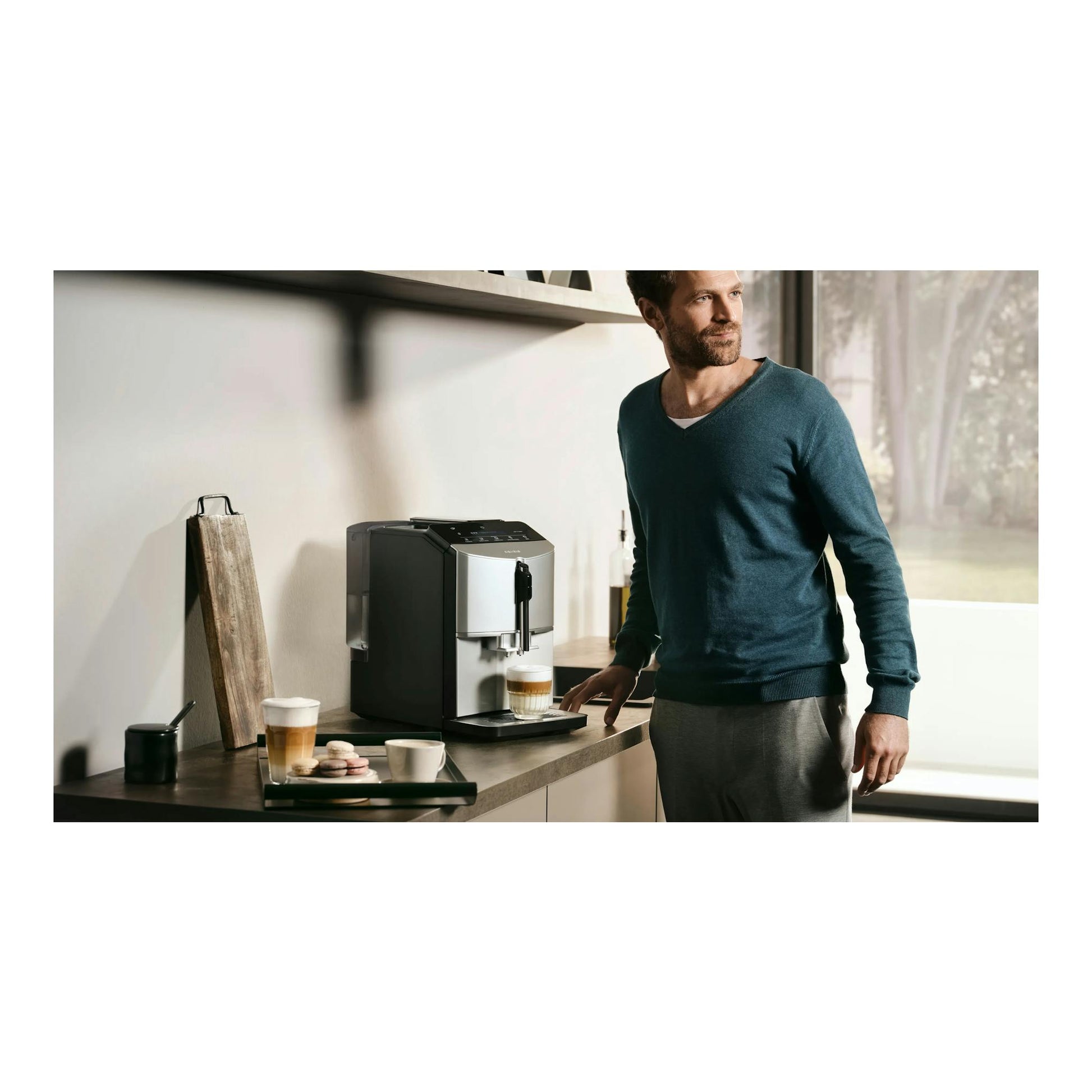 Cafetera superautomática Siemens negra y plateada, vista frontal tres cuartos, sobre encimera, con una taza.