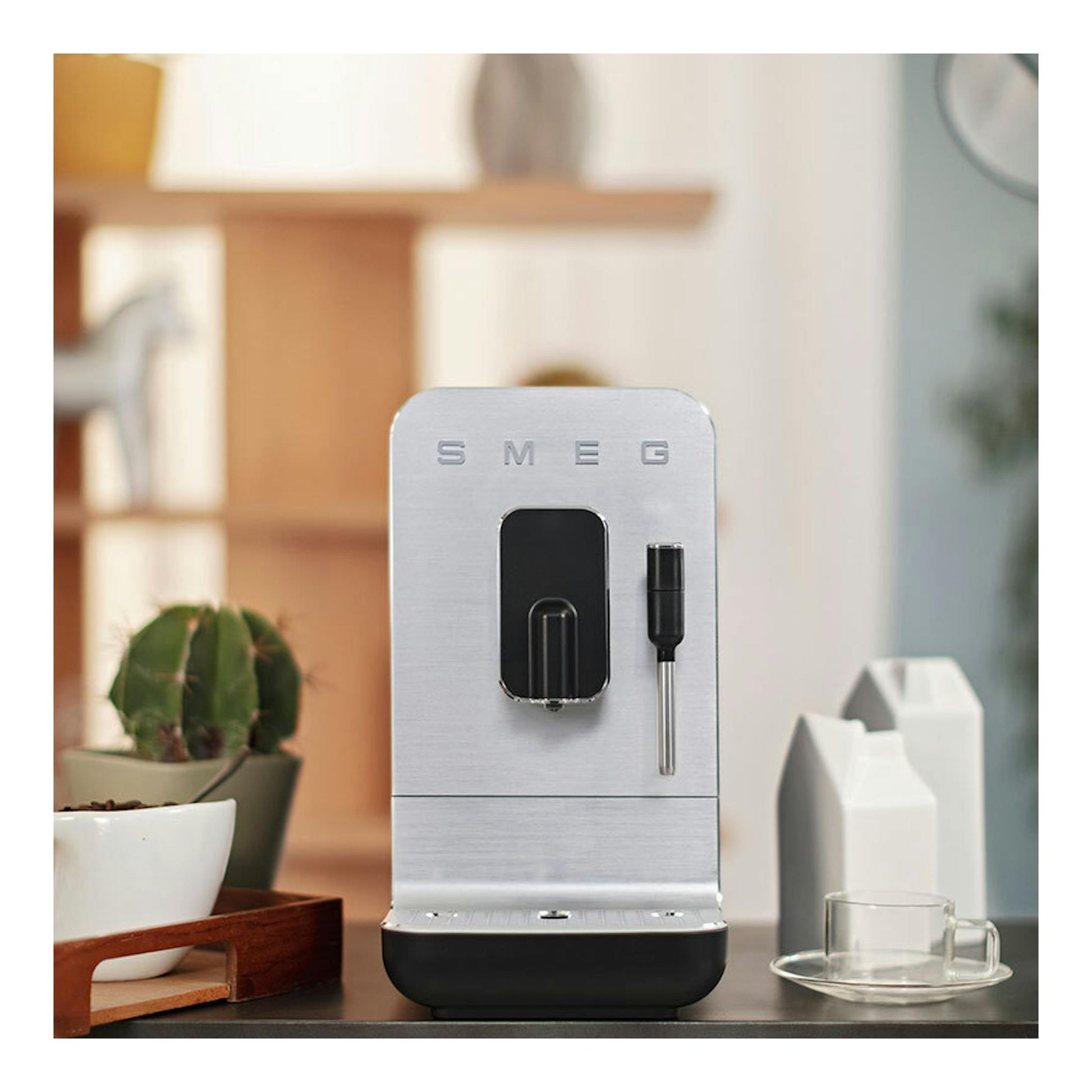 Cafetera superautomática Smeg BCC12BLMEU, vista frontal, en acero inoxidable con base negra.