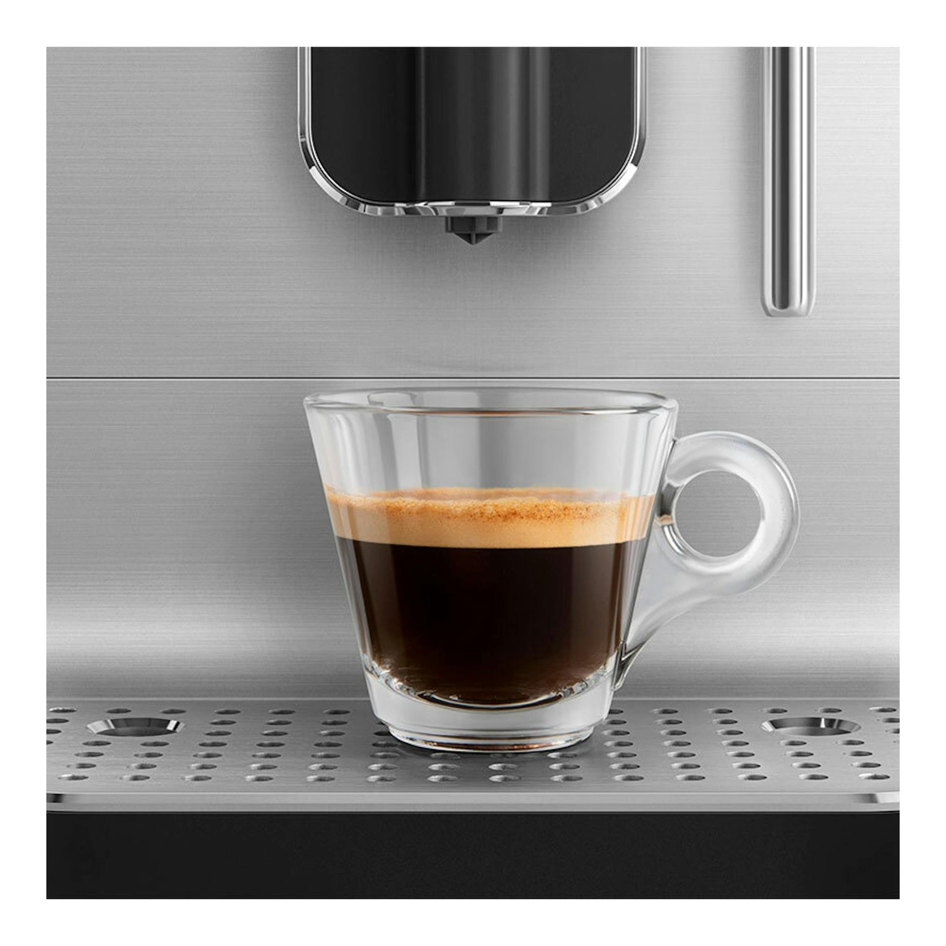 Cafetera superautomática Smeg BCC12BLMEU, vista frontal, dispensando espresso en una taza de vidrio.
