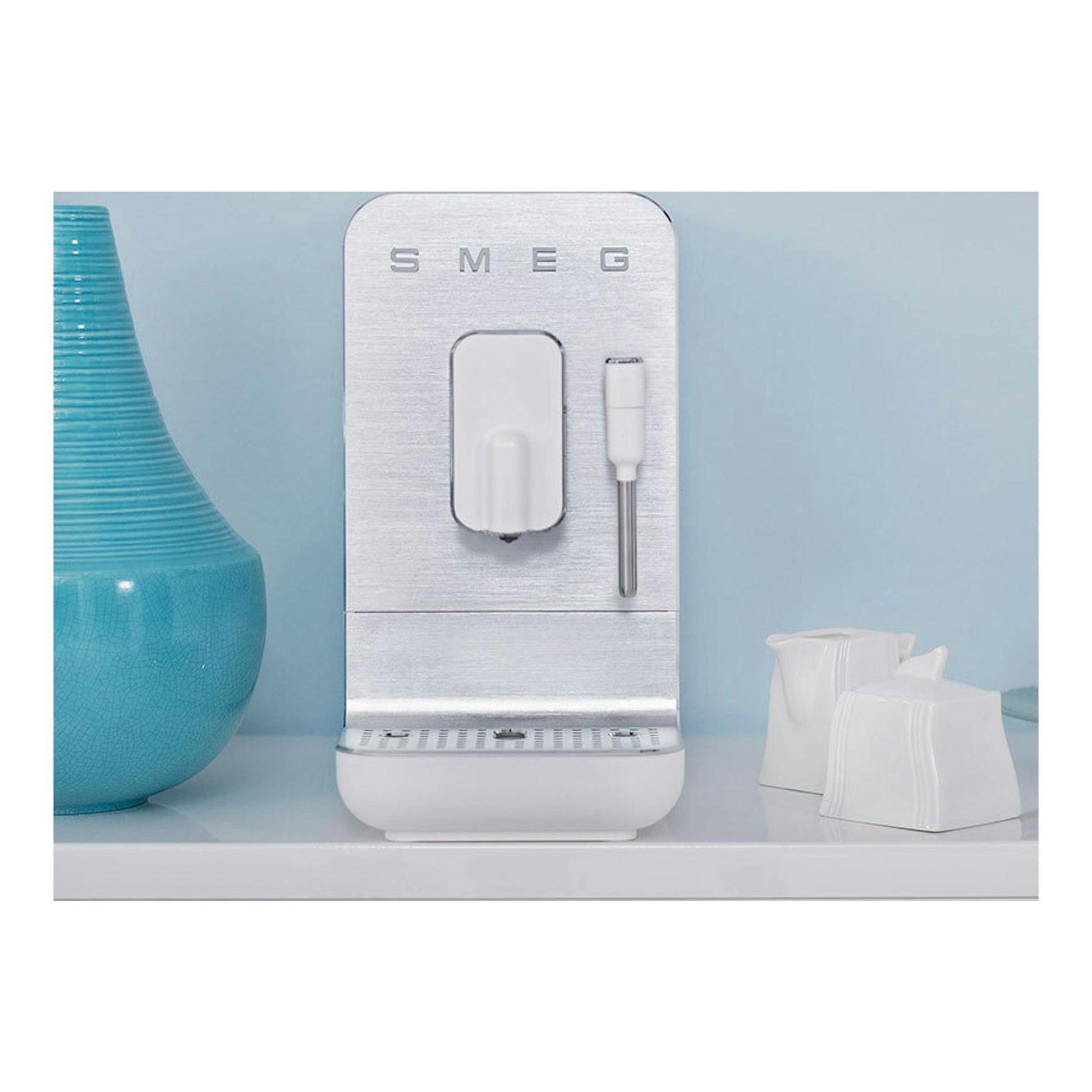 Cafetera superautomática Smeg BCC12WHMEU, vista frontal en blanco y plata, con espumador lateral.