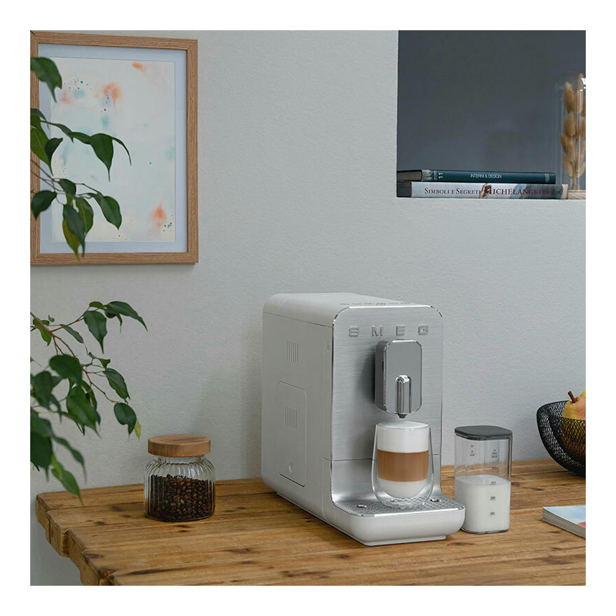 Cafetera superautomática Smeg BCC13WHMEU blanca, vista frontal, con taza en la bandeja.