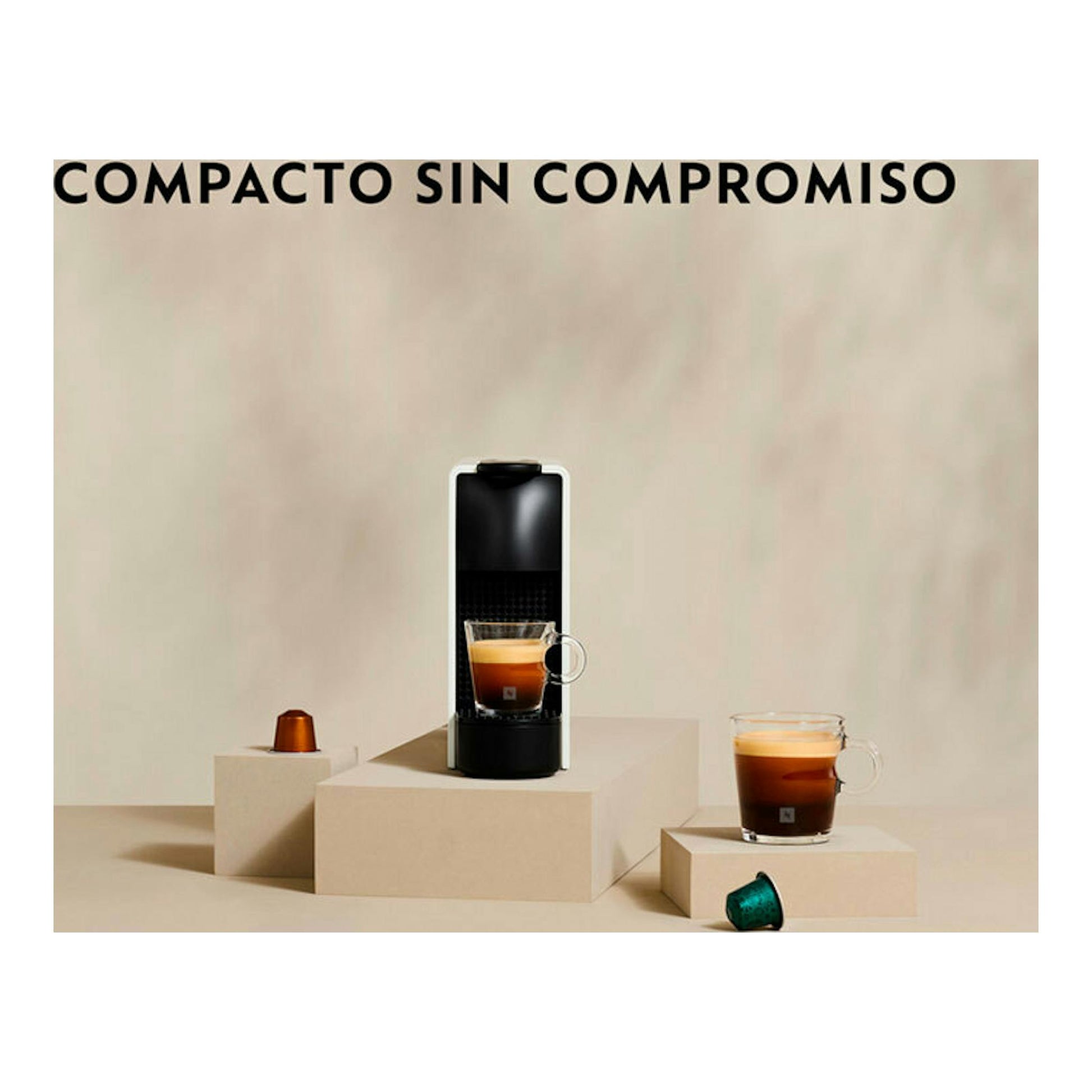 Cafetera Nespresso Krups XN1108RD negra, vista frontal, sobre fondo beige, con dos tazas y cápsulas.