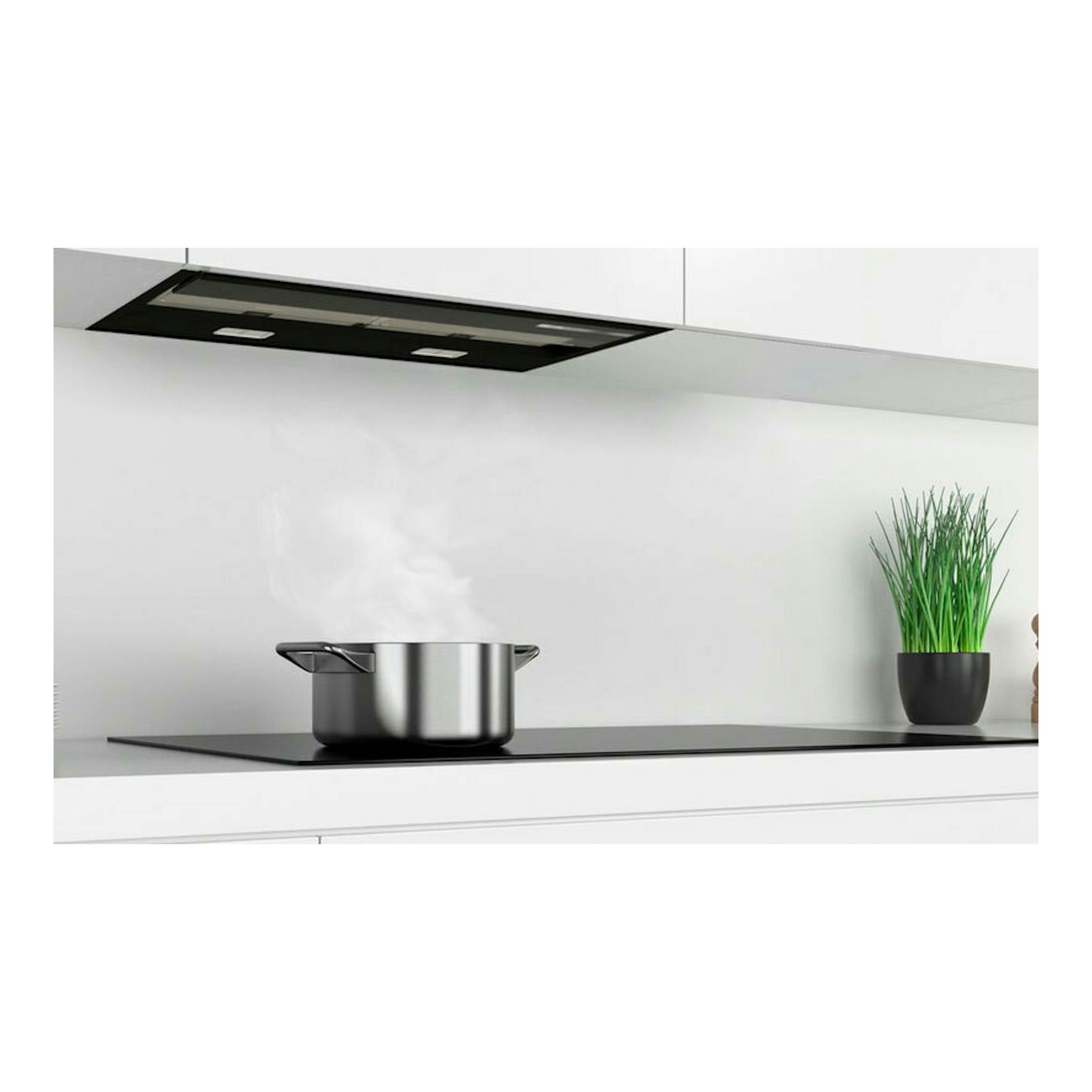 Campana extractora Bosch DBB67AM60 negra y acero inoxidable, vista inferior sobre una cocina blanca.