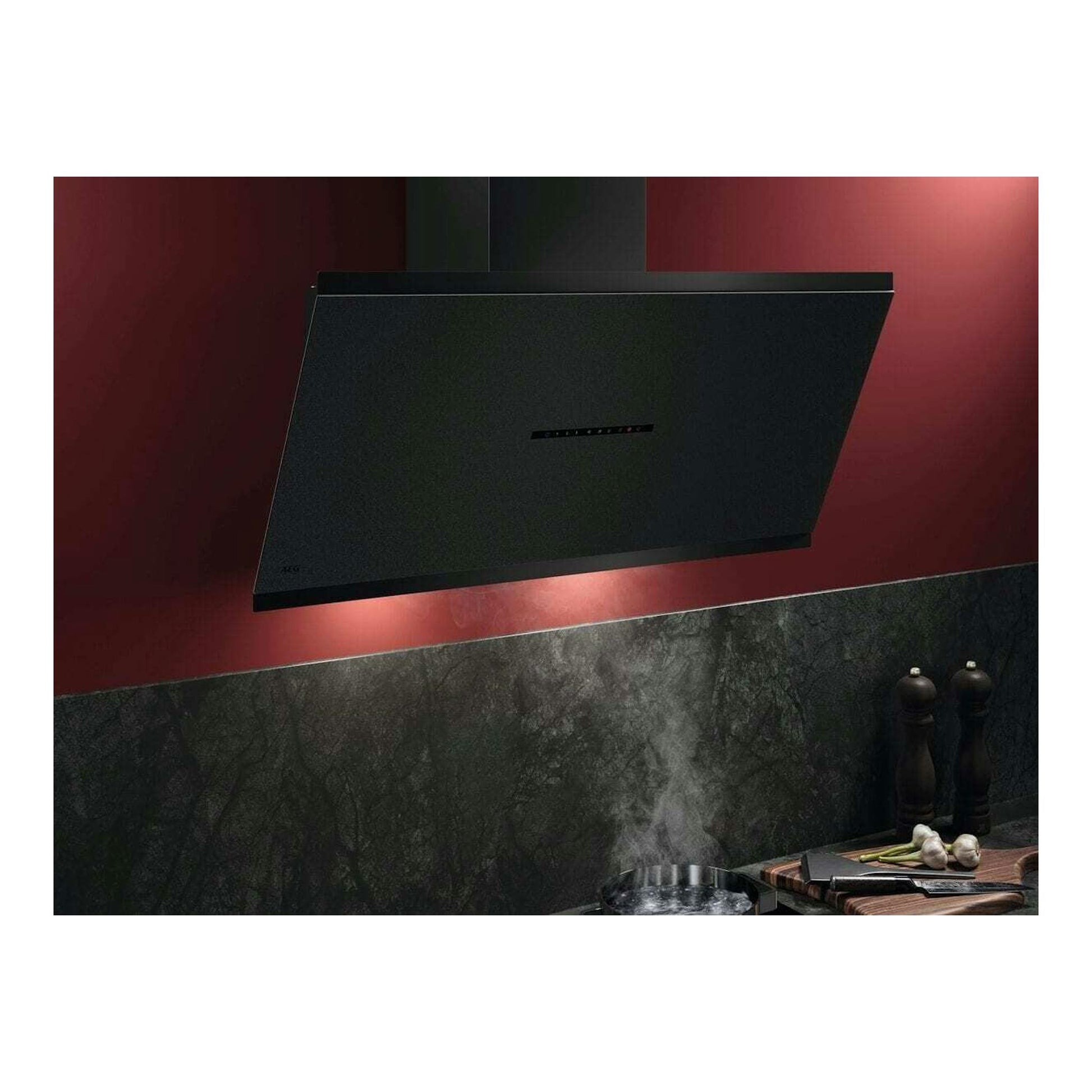 Campana decorativa AEG GV77D91SZ negra, vista frontal inclinada, sobre pared roja de cocina.