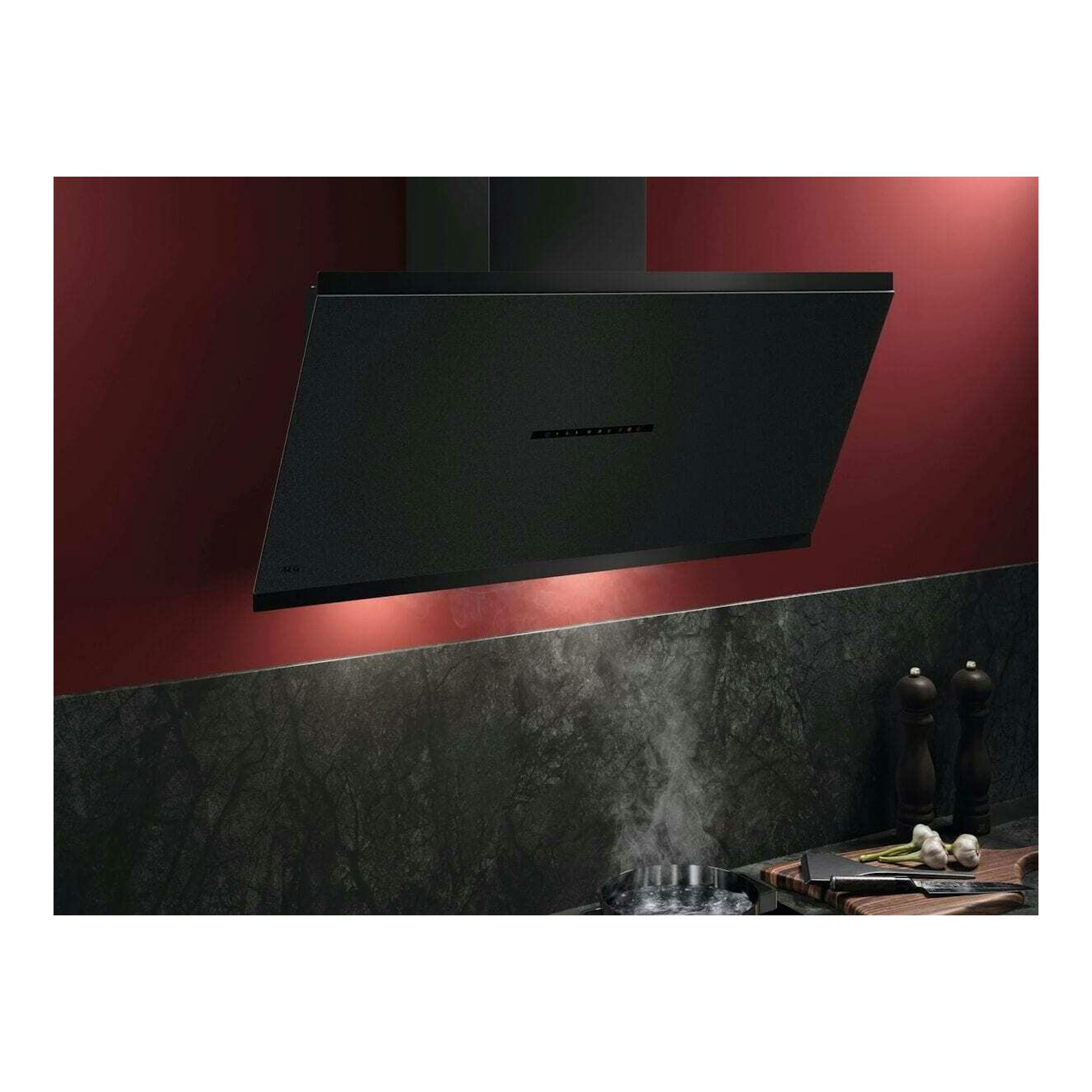 Campana decorativa AEG GV77D91SZ negra, vista frontal inclinada, sobre pared roja de cocina.