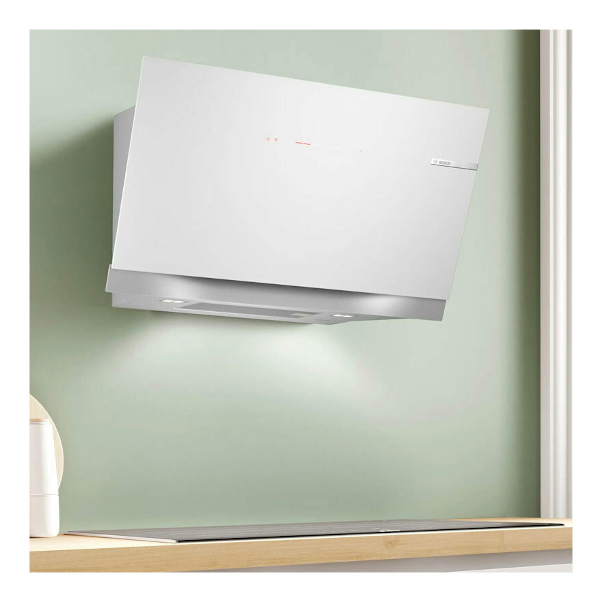 Campana extractora decorativa Bosch blanca, vista frontal inclinada, montada en pared verde.