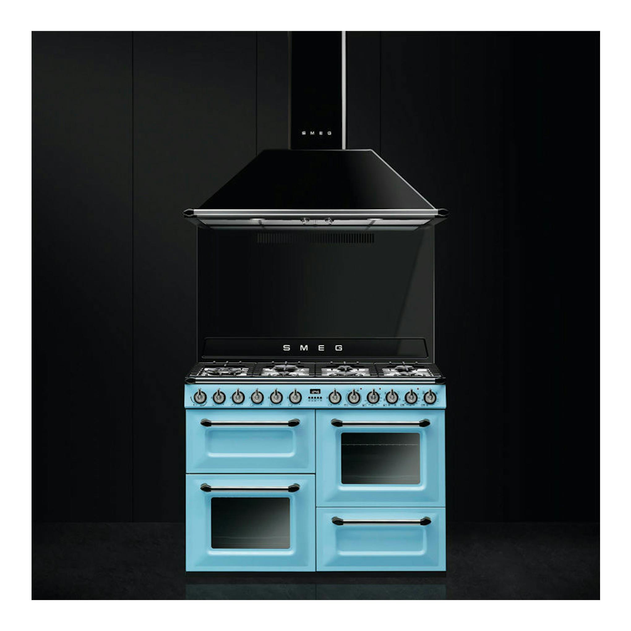 Campana decorativa Smeg KT110BLE negra, vista frontal, sobre cocina azul.