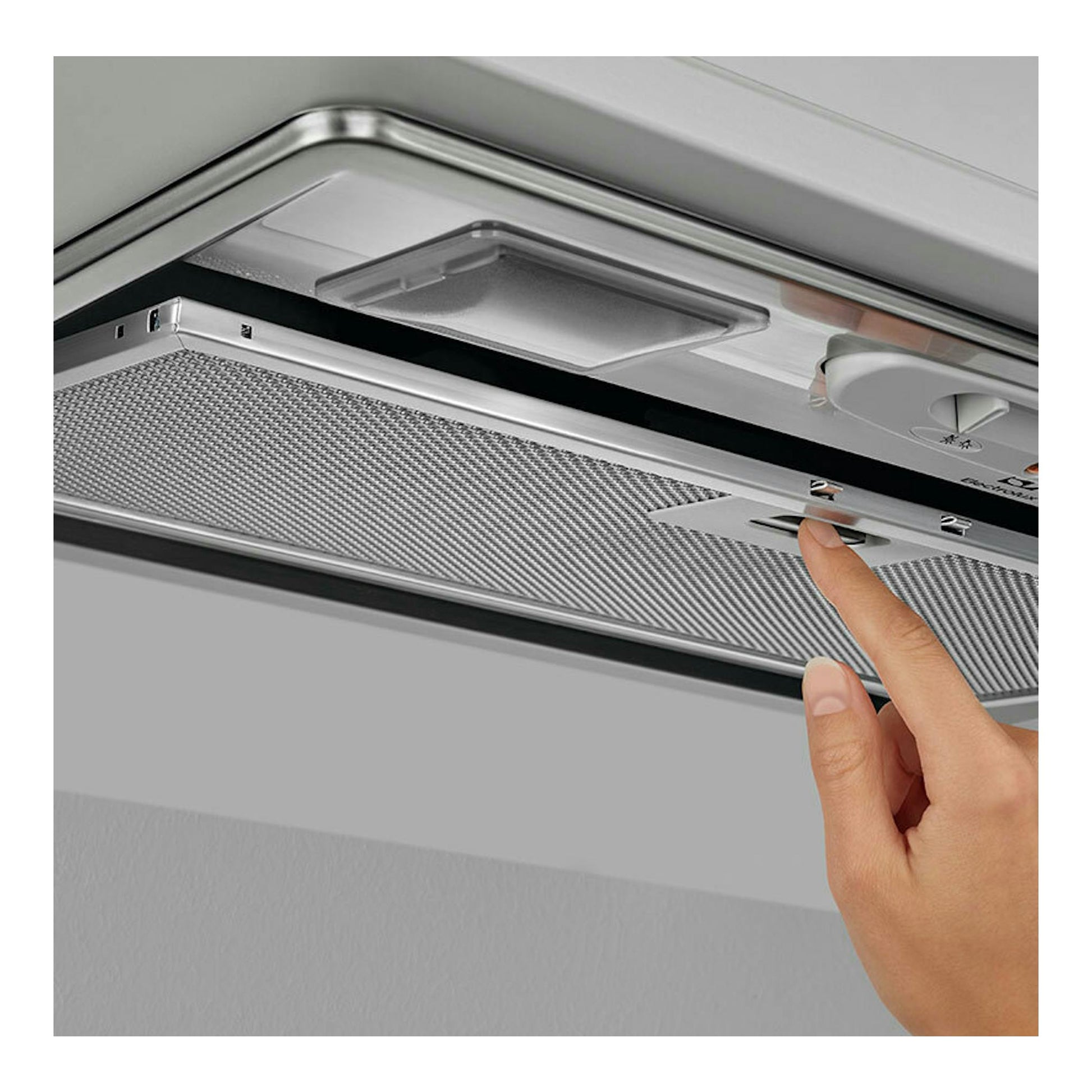 Campana extractora Electrolux LFG235S inox, vista inferior, con una mano pulsando un botón.