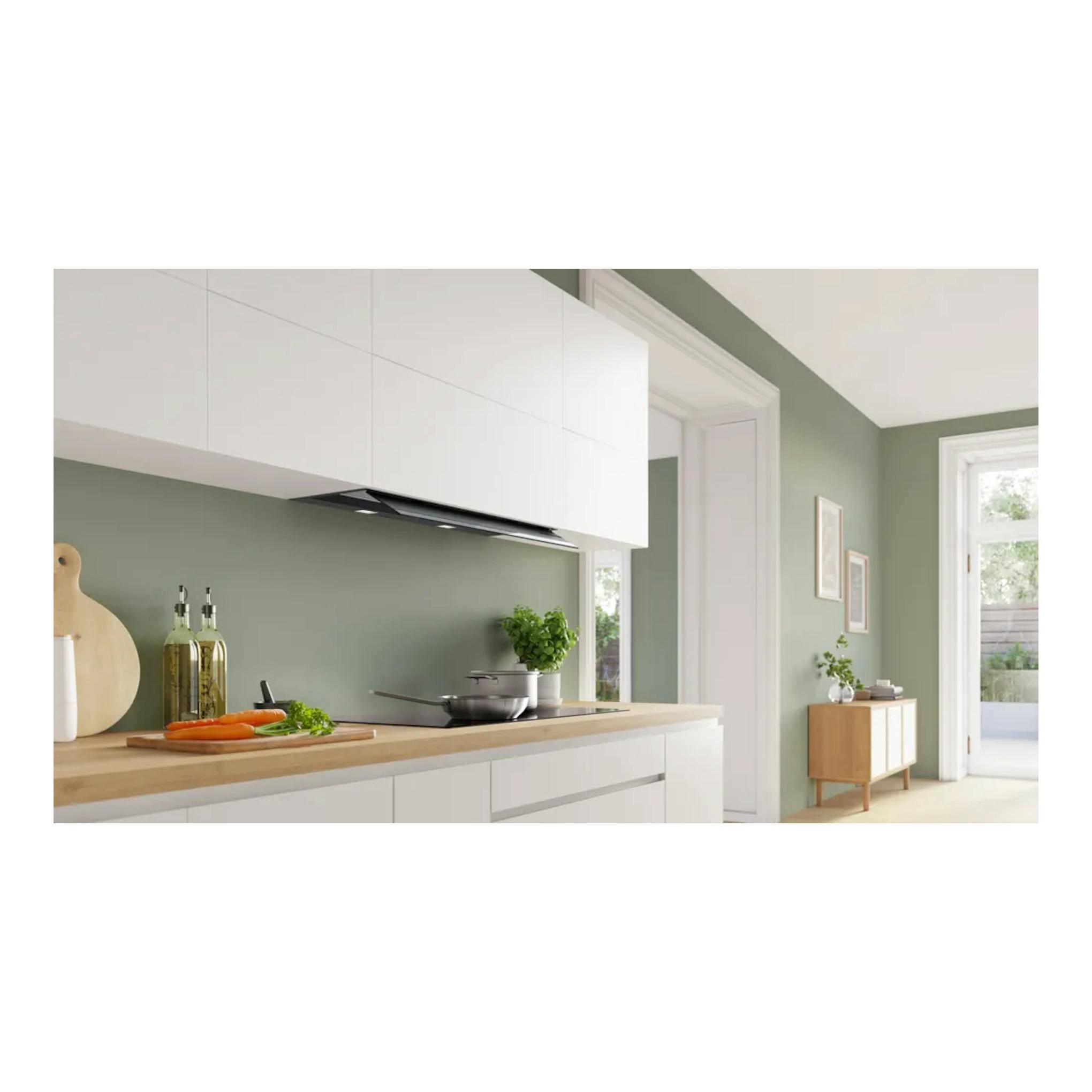 Campana extractora Bosch DBB97DP60 negra integrada bajo armarios blancos, vista frontal en cocina.
