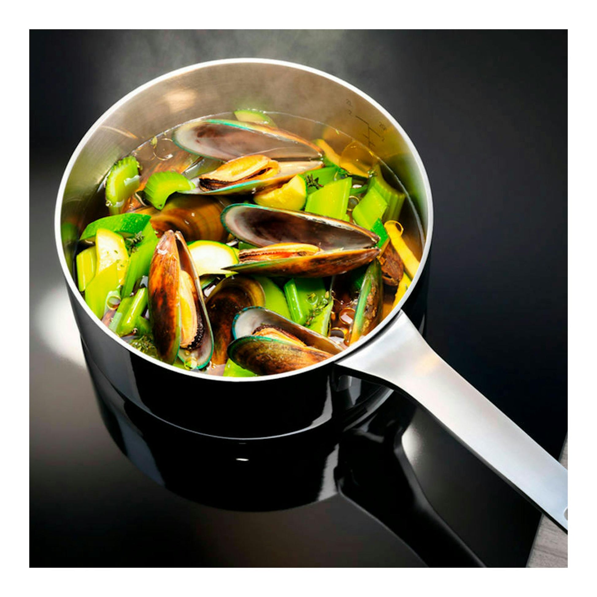 Cazuela de acero inoxidable con mejillones y verduras, vista cenital sobre fondo negro.
