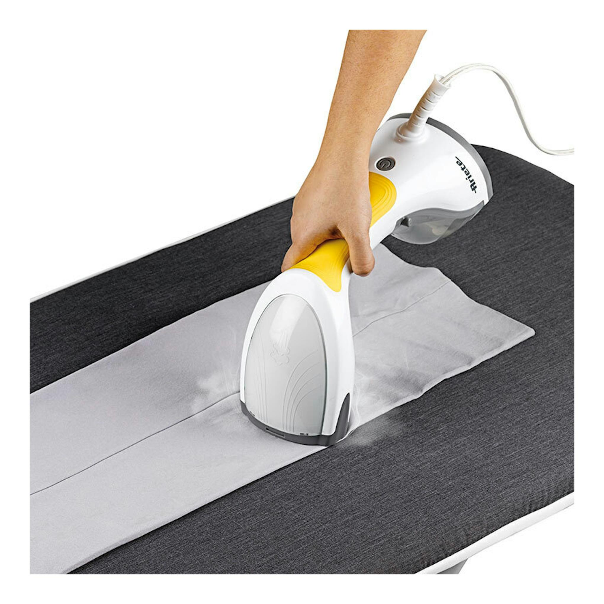Cepillo de vapor portátil Ariete en blanco y amarillo, sobre una camisa gris, visto en uso con cable.