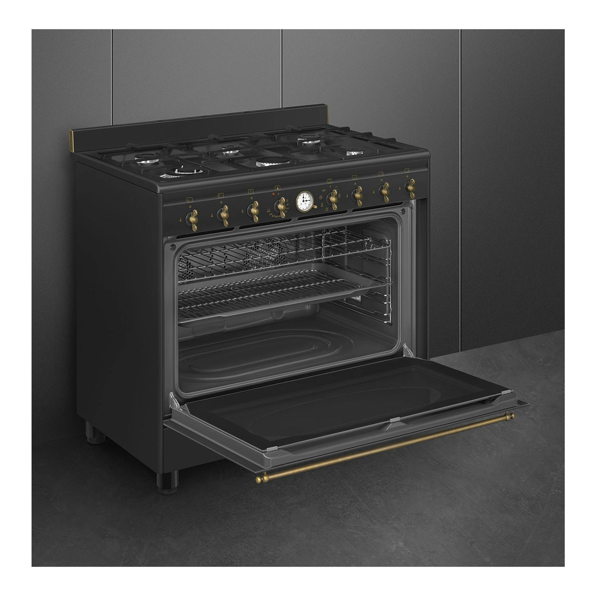 SMEG CO90GMAN2: cocina de gas antracita, vista frontal en ángulo, con horno abierto y mandos dorados.