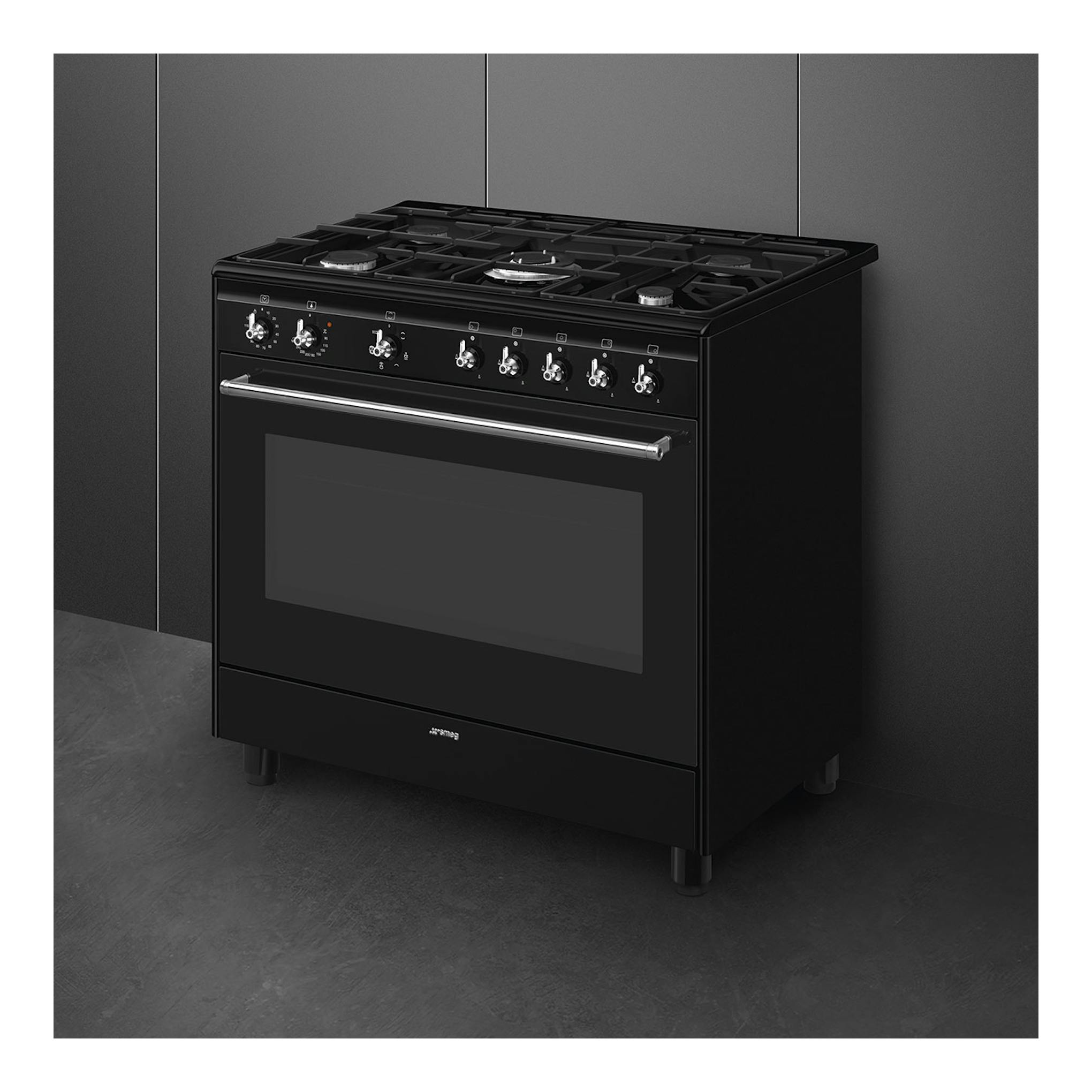 Cocina Smeg CX91GMBL negra, vista frontal en ángulo, con 5 quemadores y horno eléctrico.