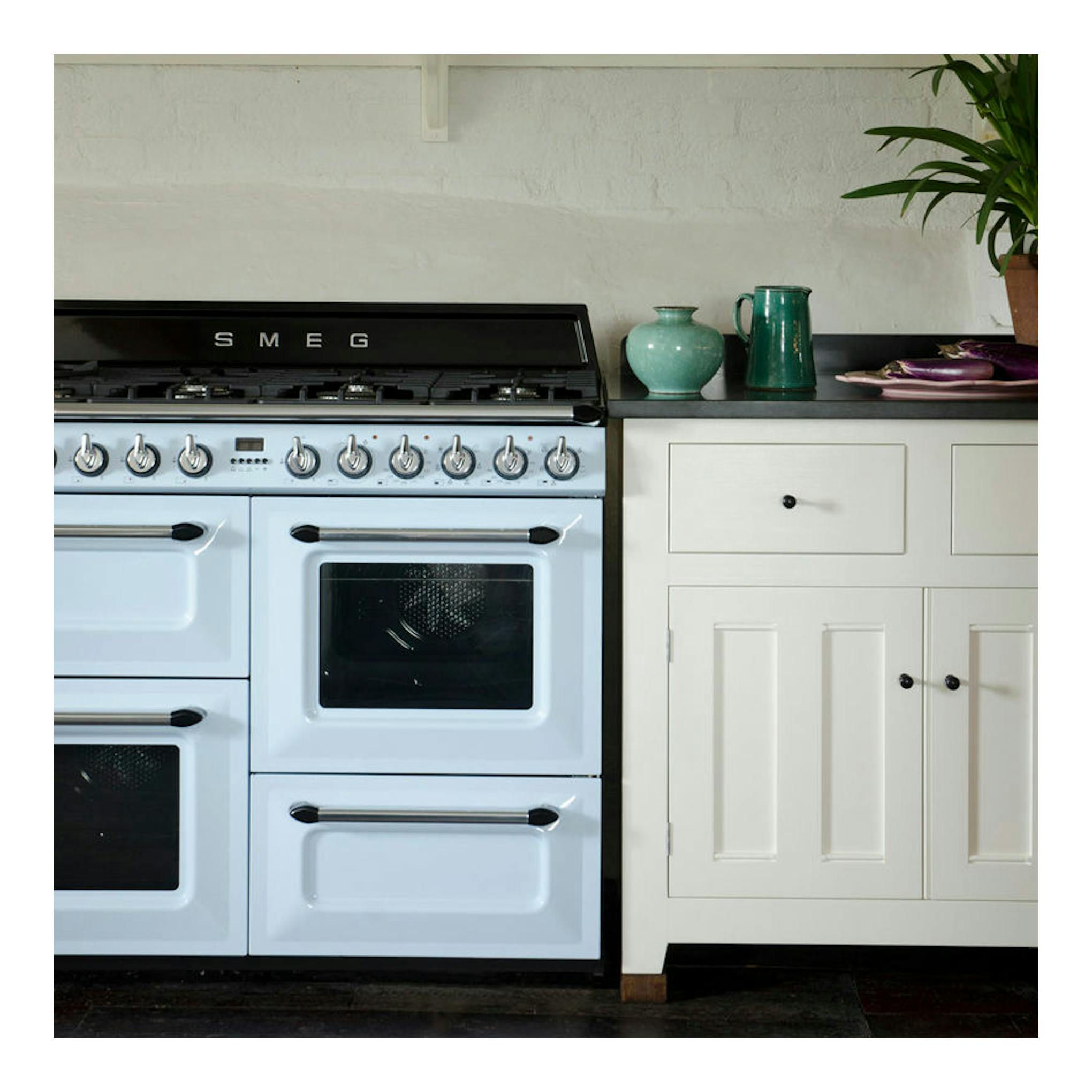 Cocina Smeg TR4110AZ azul claro, vista frontal, con varios hornos y mandos cromados.