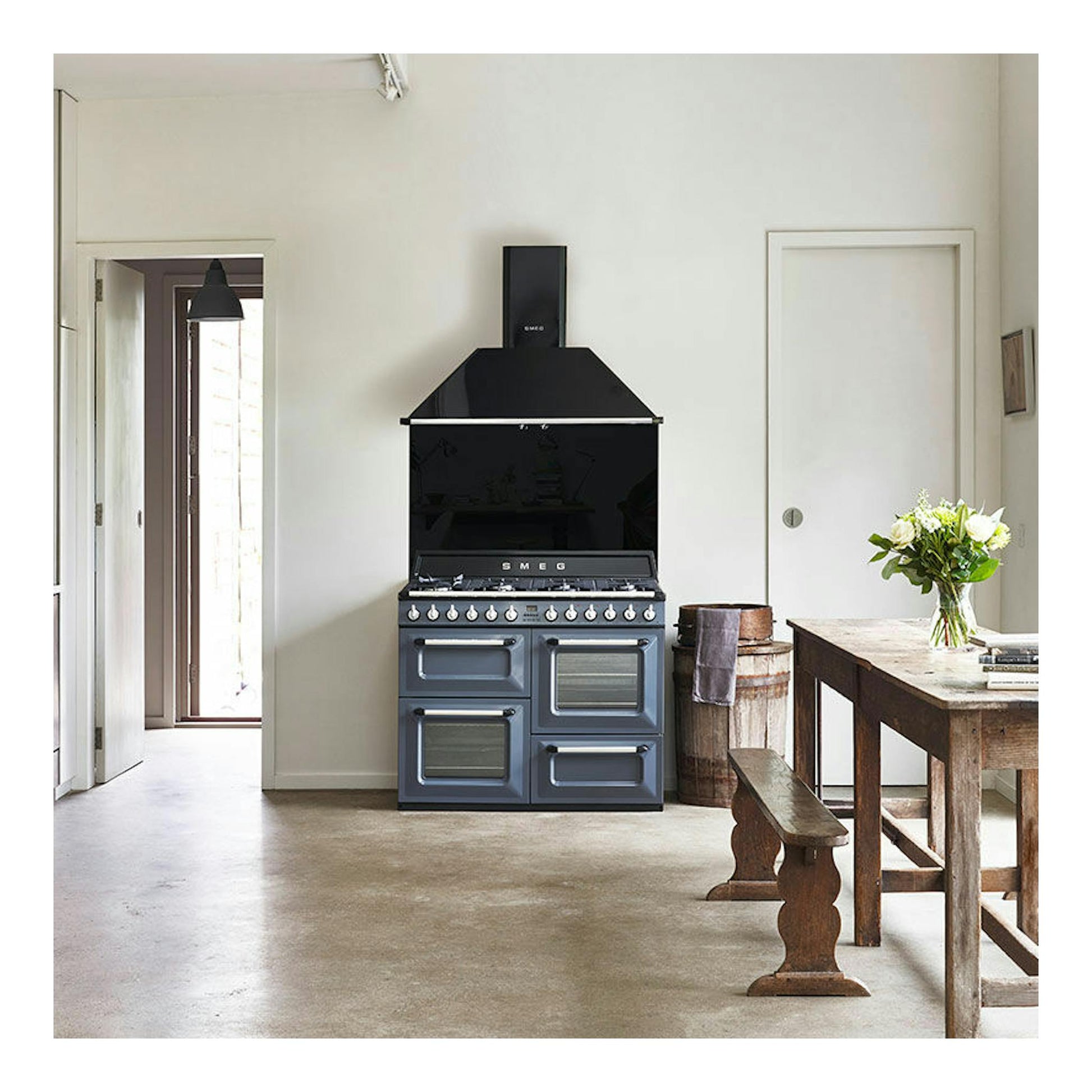 Cocina Smeg TR4110GR de 110 cm, vista frontal, en gris azulado y negro, con campana integrada.