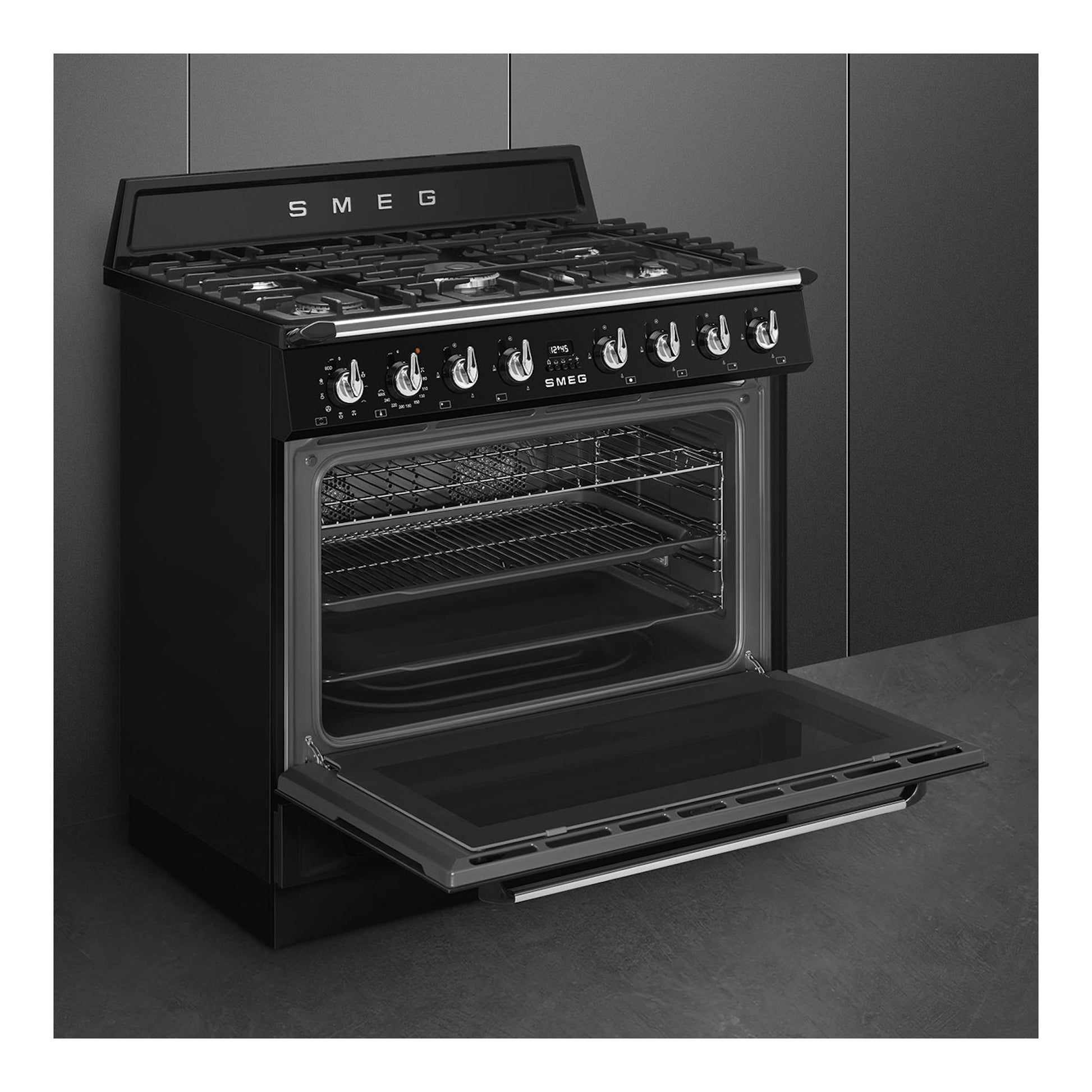 Cocina Smeg TR90GMBL negra, vista frontal en tres cuartos, con horno abierto y cinco fuegos.