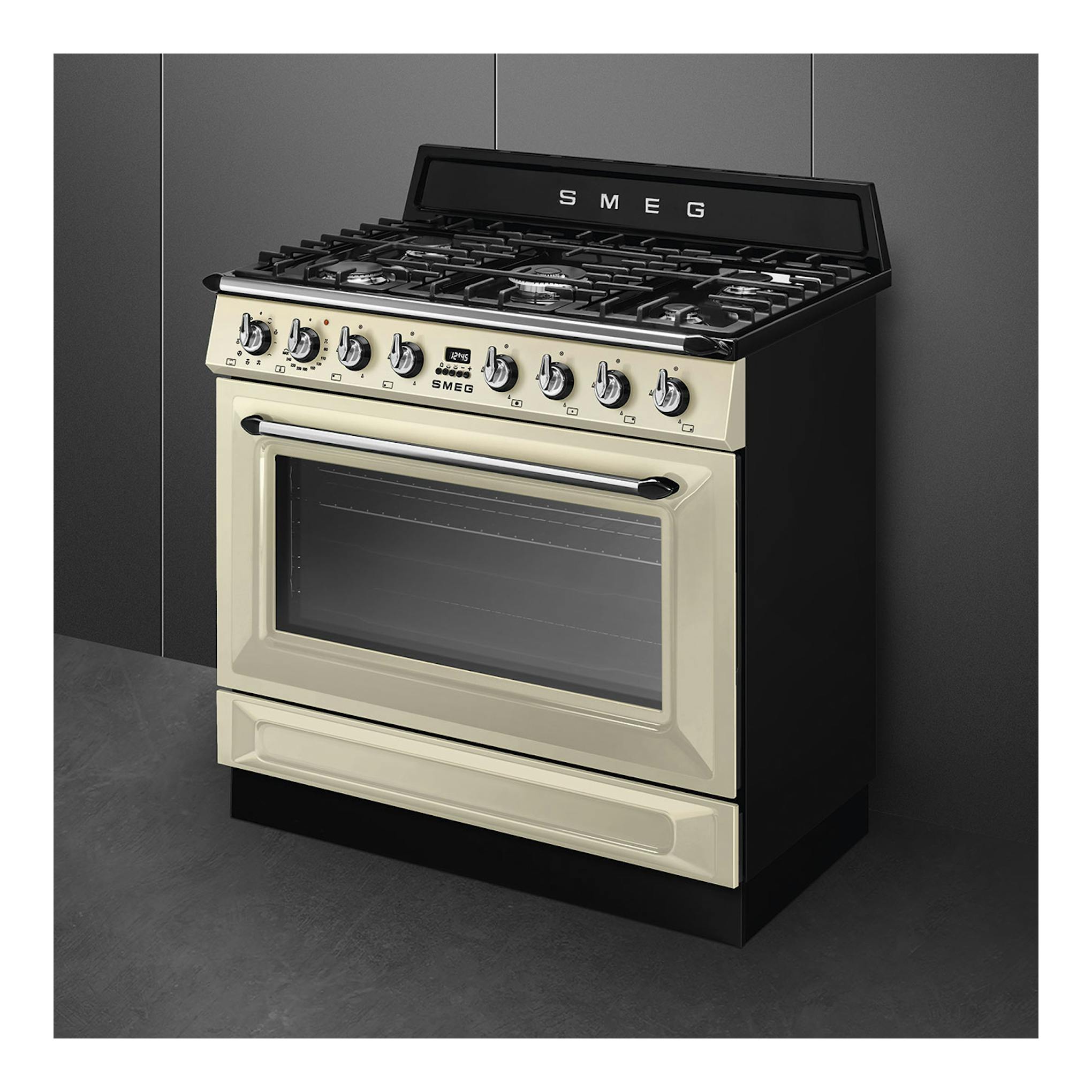 Cocina Smeg TR90GMP de gas, color crema y negro, vista frontal en ángulo, con horno y mandos.