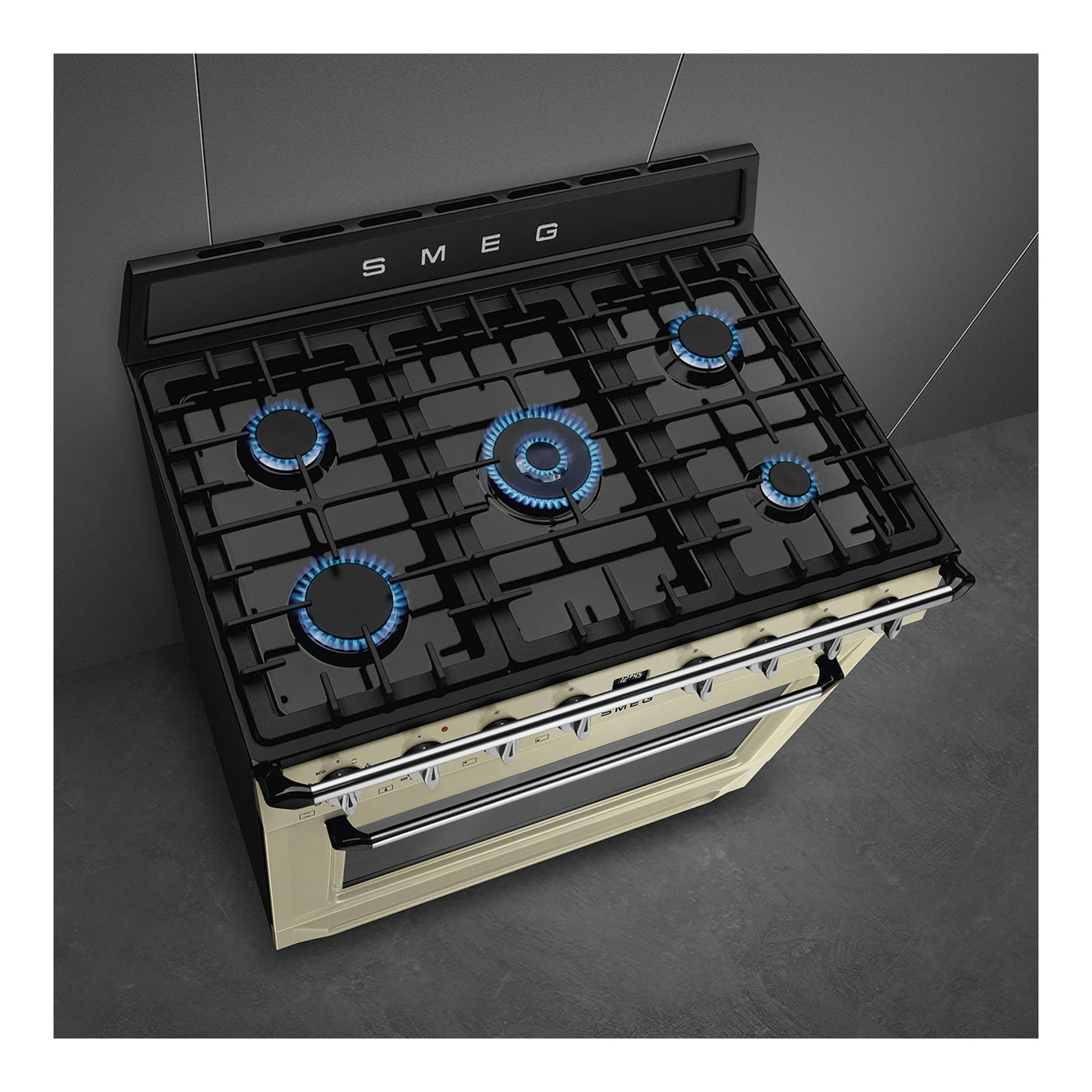 Cocina Smeg TR90GMP negra y crema, vista en ángulo superior, con 5 fuegos encendidos.