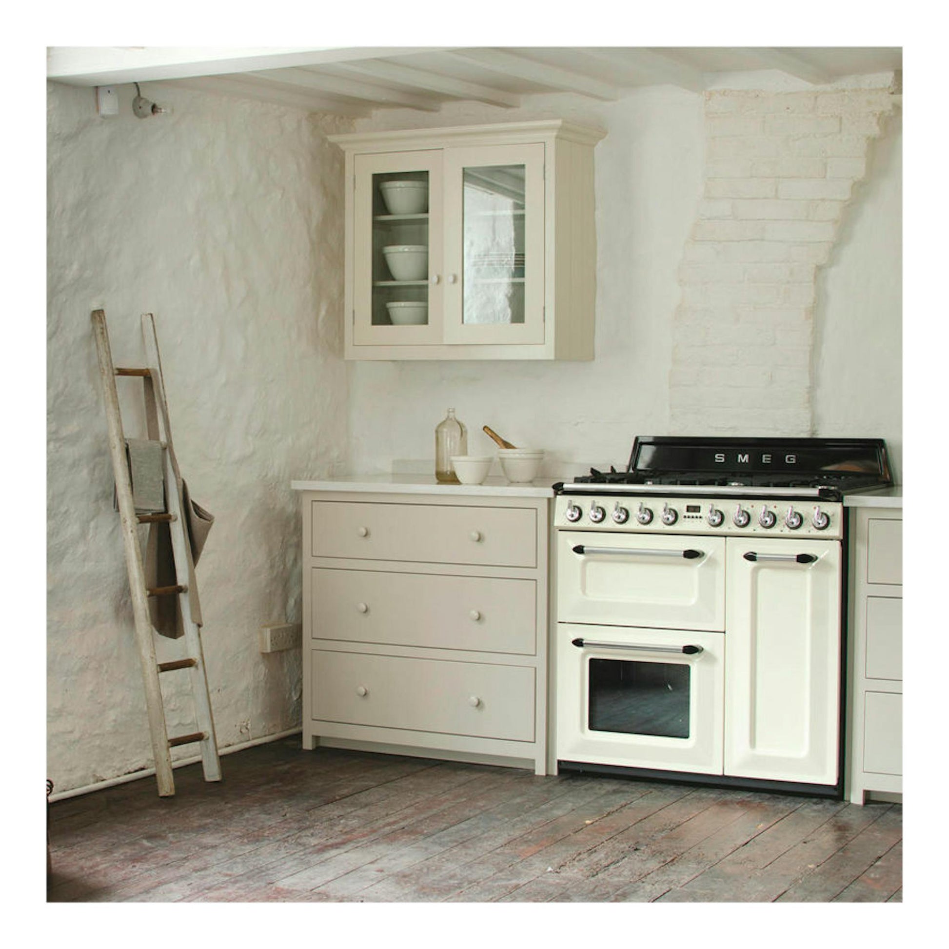 Cocina Smeg TR93P blanca de 90 cm, vista frontal, en cocina rústica con muebles beige.