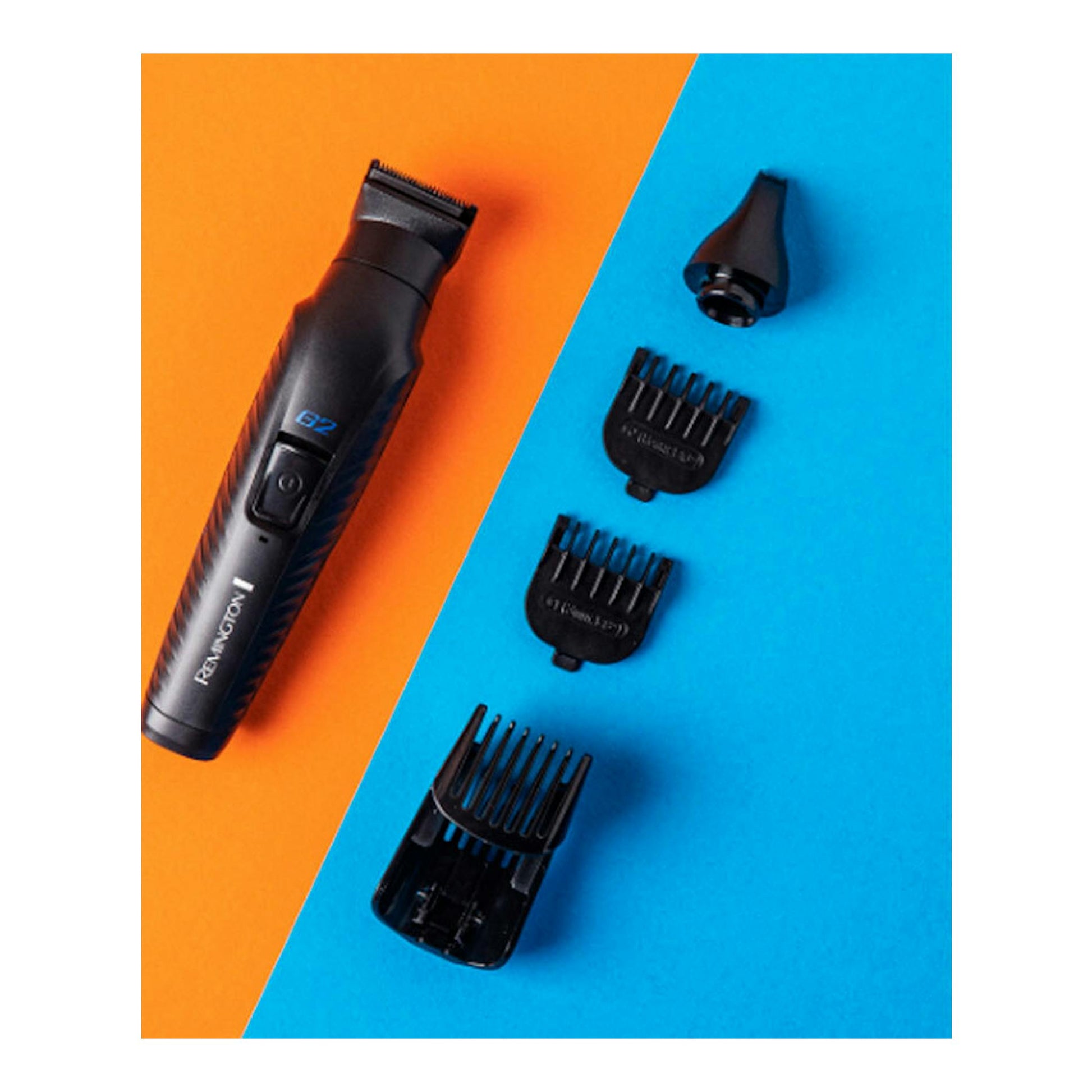 Cortapelos Remington PG2000 negro, vista cenital, con peines guía y accesorios sobre fondo naranja y azul.