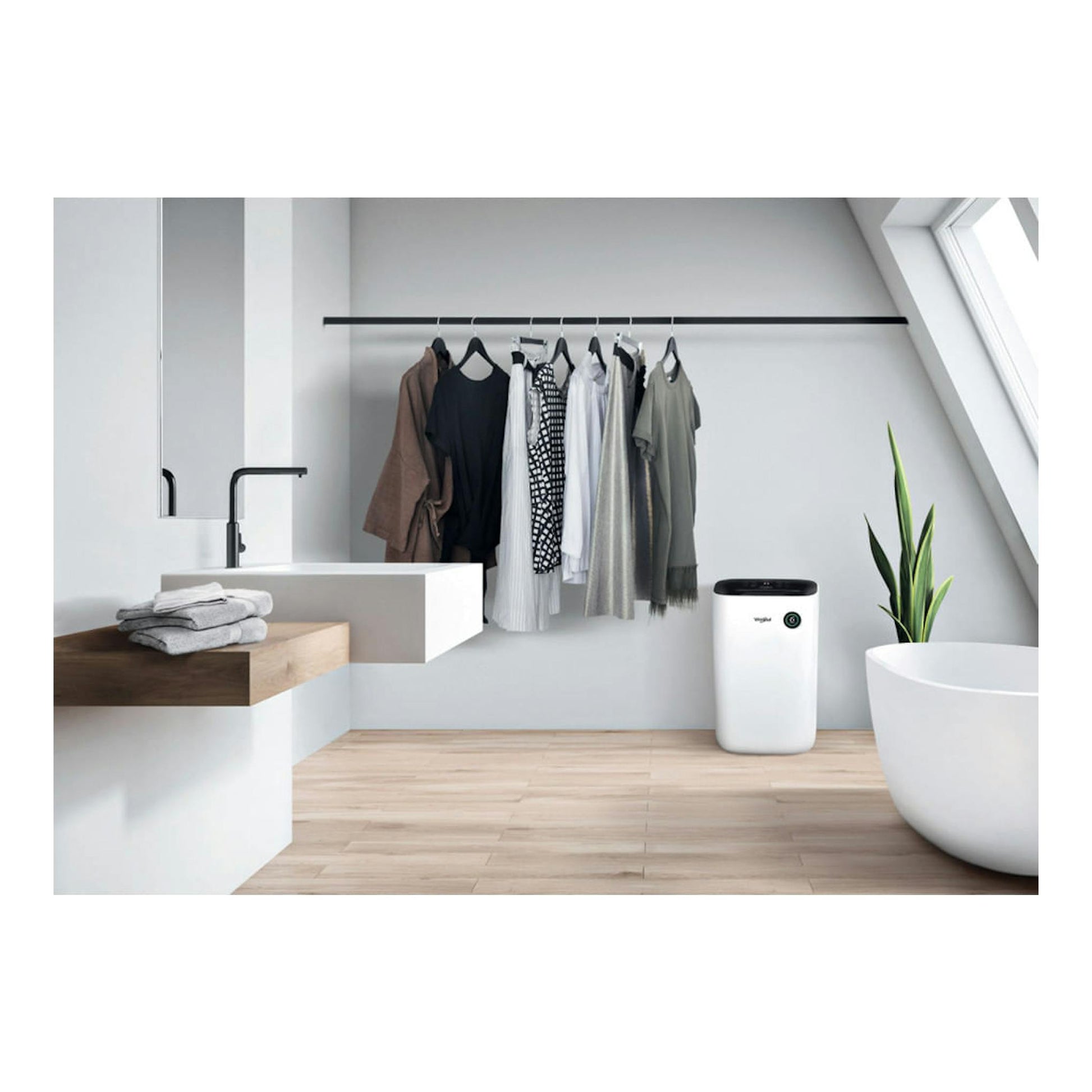 Deshumidificador Whirlpool DE20W5252 blanco, vista frontal, junto a ropa tendida en un baño.