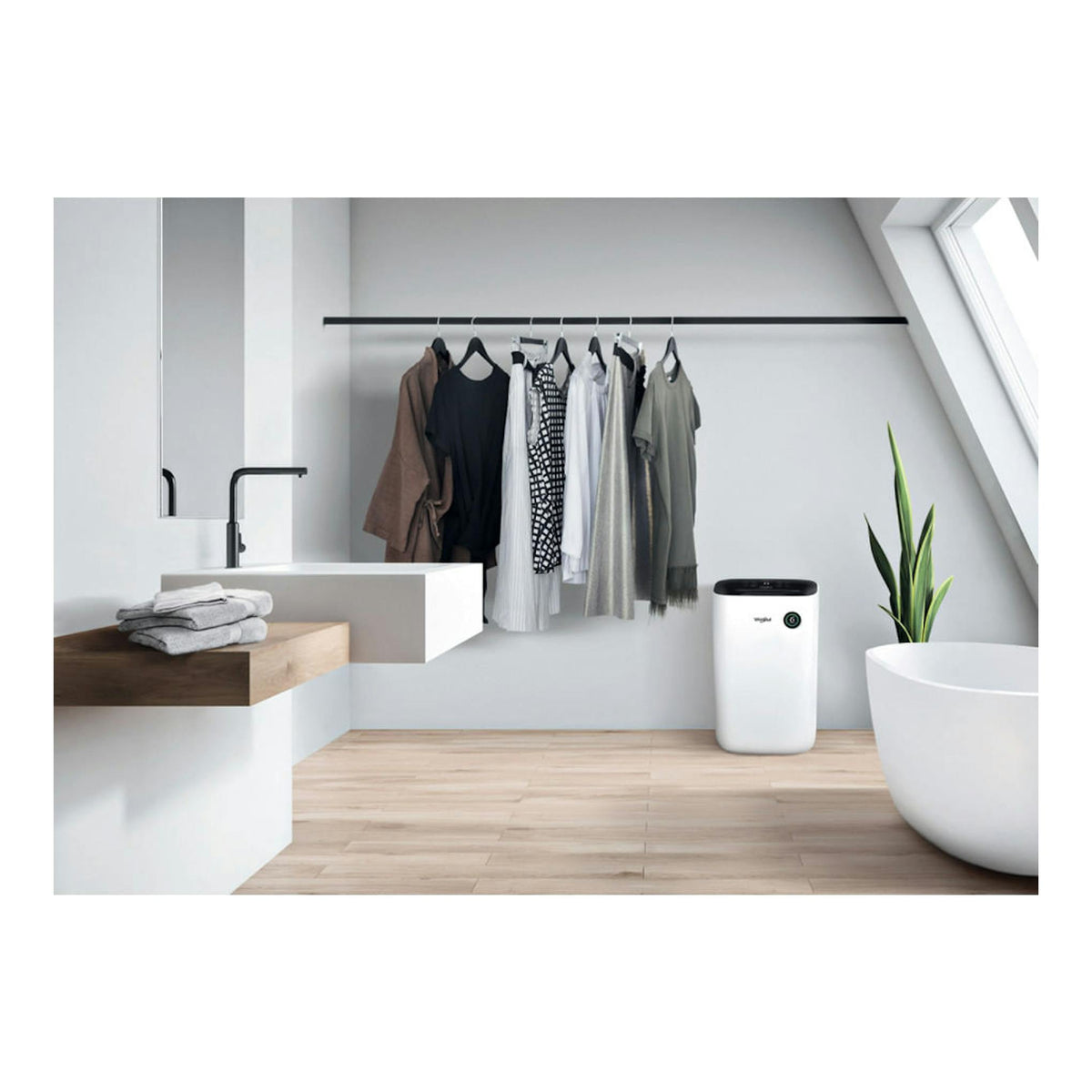 Deshumidificador Whirlpool DE20W5252 blanco, vista frontal, junto a ropa tendida en un baño.