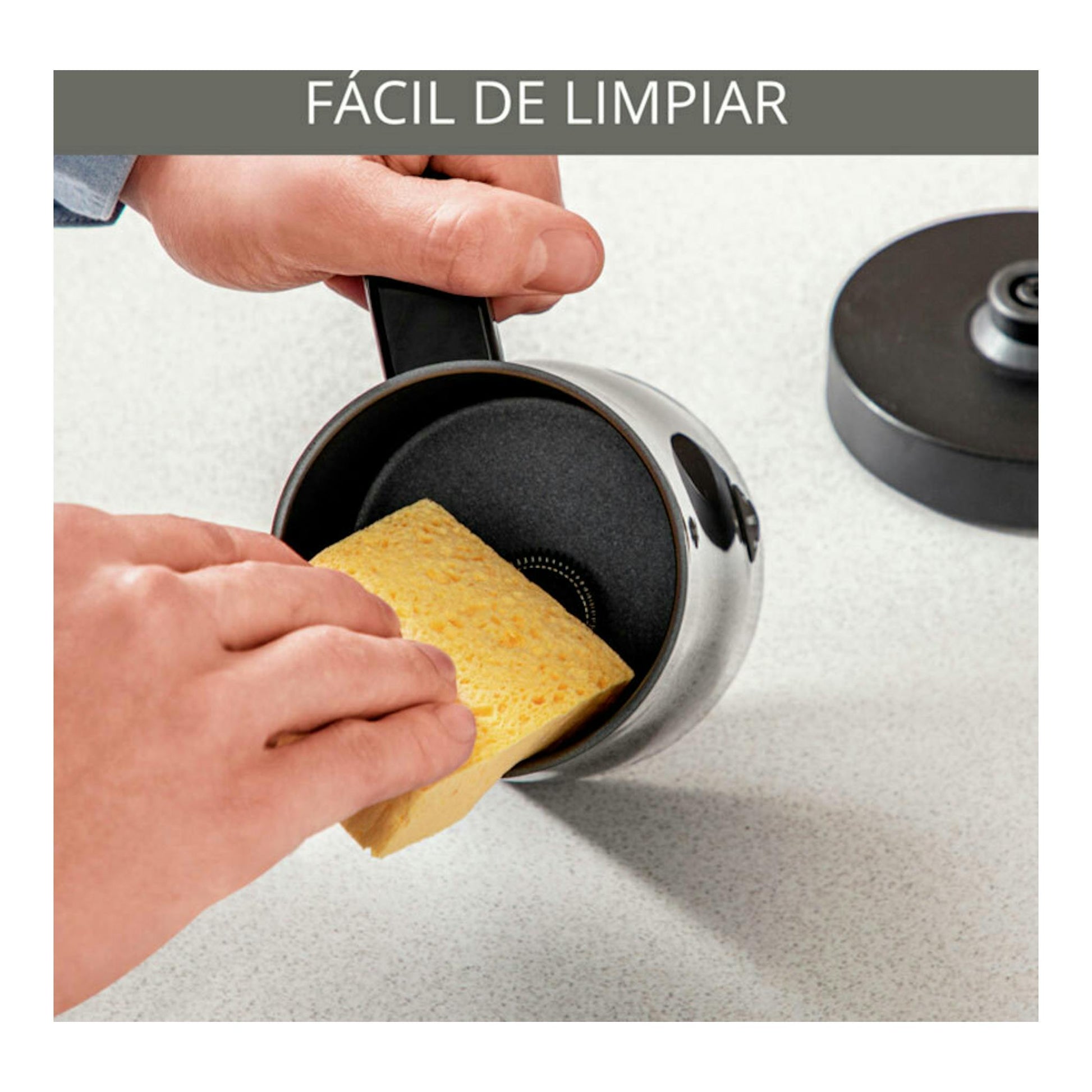 Espumador de leche Krups XL100810, visto en ángulo, interior negro y plateado, limpiándose con una esponja.