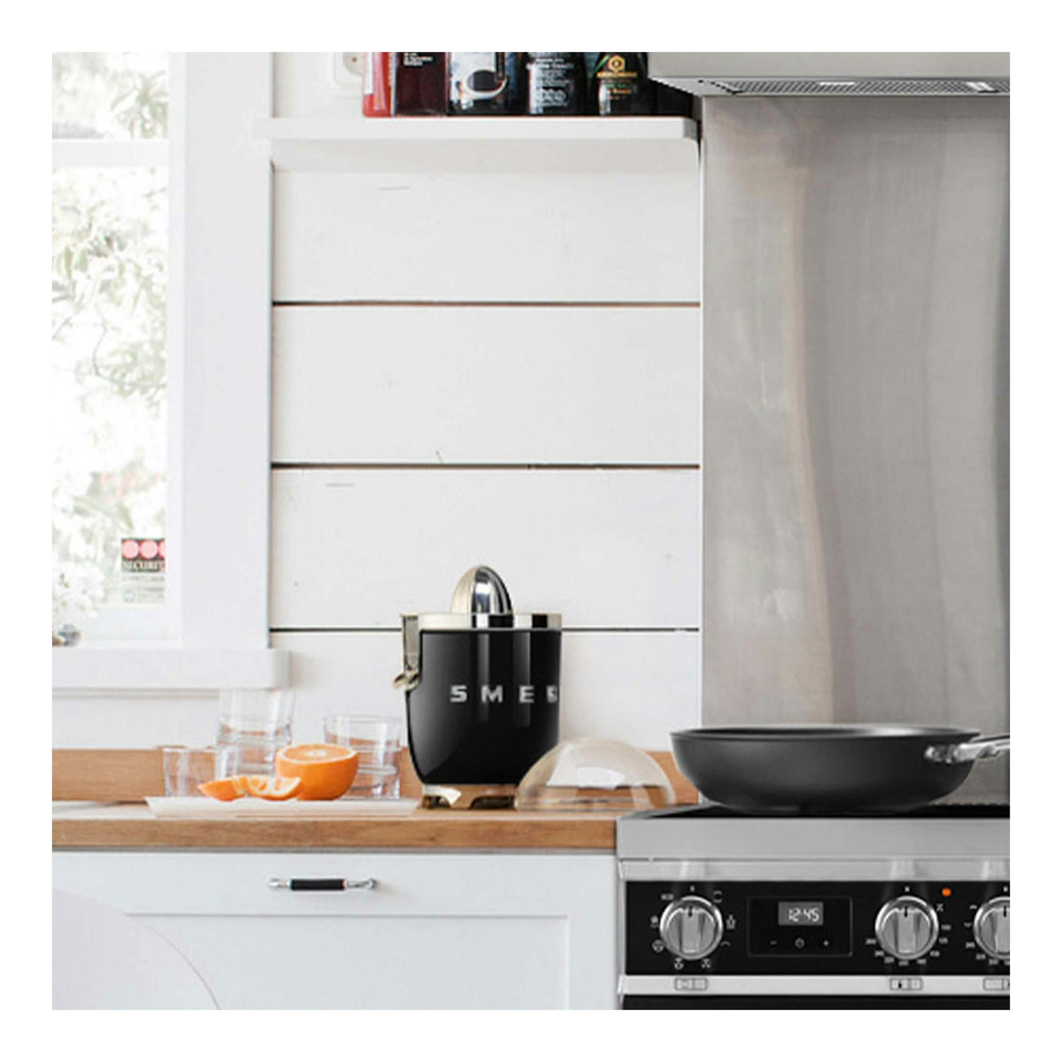 Exprimidor Smeg CJF01BLEU negro sobre una encimera de cocina, vista frontal.
