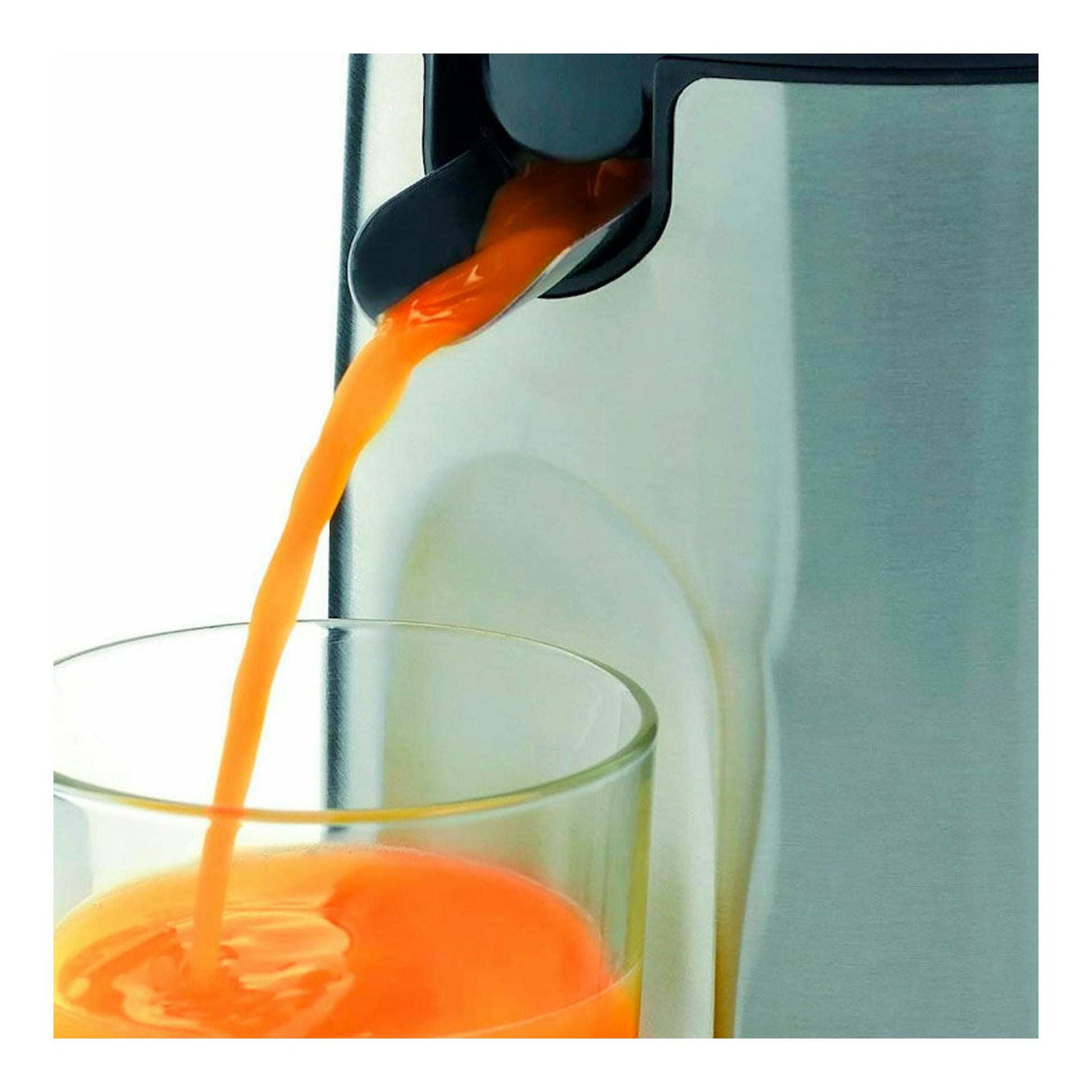 Exprimidor WMF Stelio de acero inoxidable vertiendo zumo de naranja en un vaso, vista en primer plano.