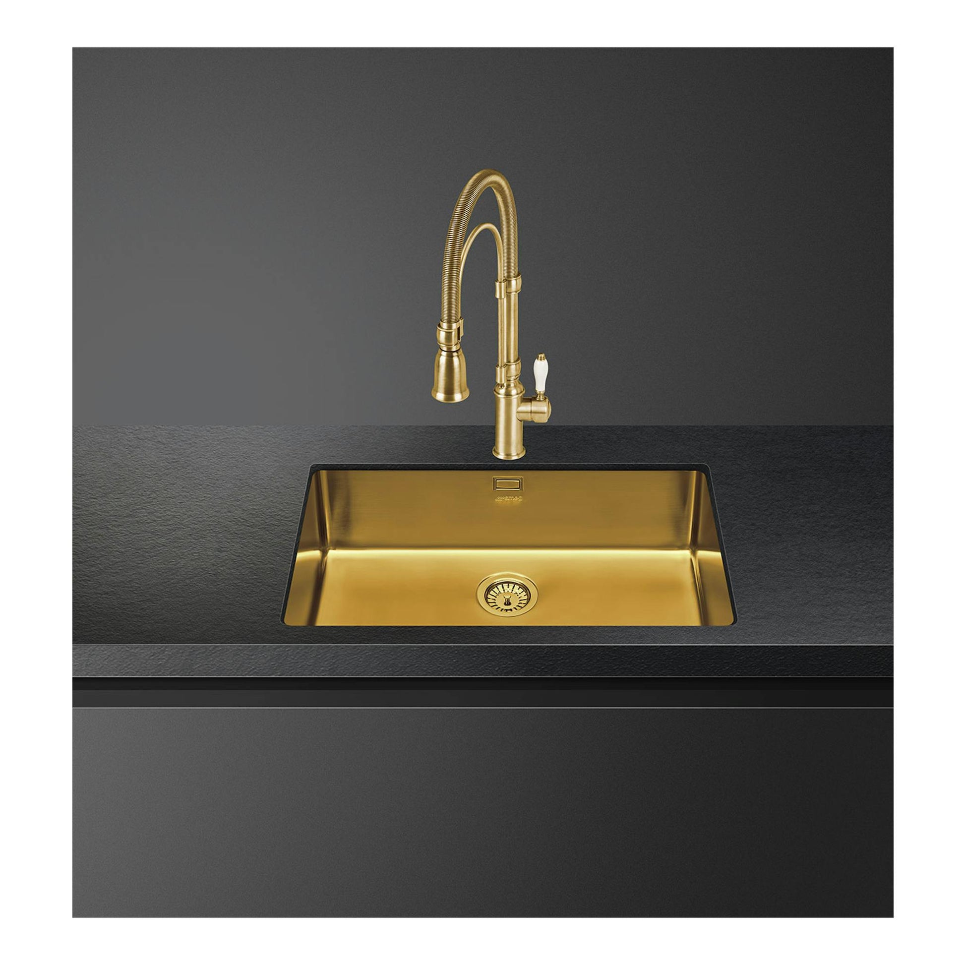 Fregadero bajo encimera Smeg VSTR71BRX, vista frontal, cubeta única dorada con grifo alto sobre encimera negra.