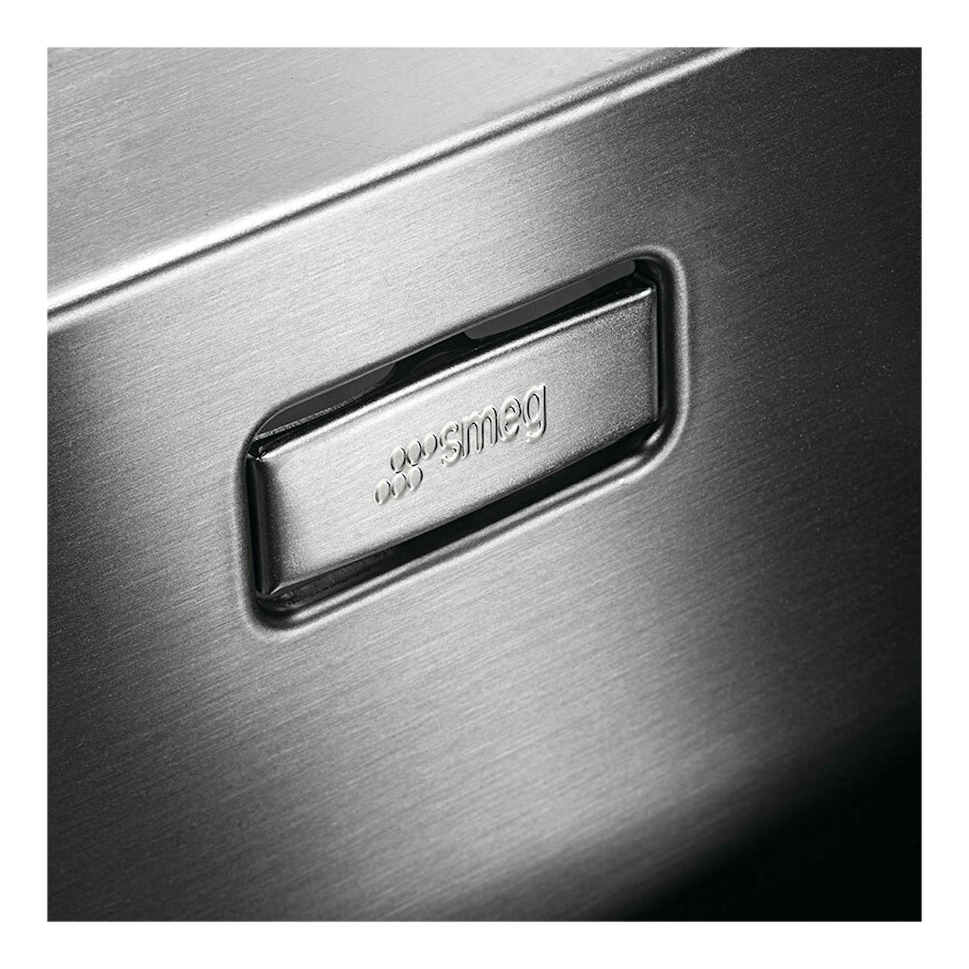 Detalle en primer plano de fregadero Smeg VR12S70 inox, con logotipo Smeg en acero inoxidable cepillado.