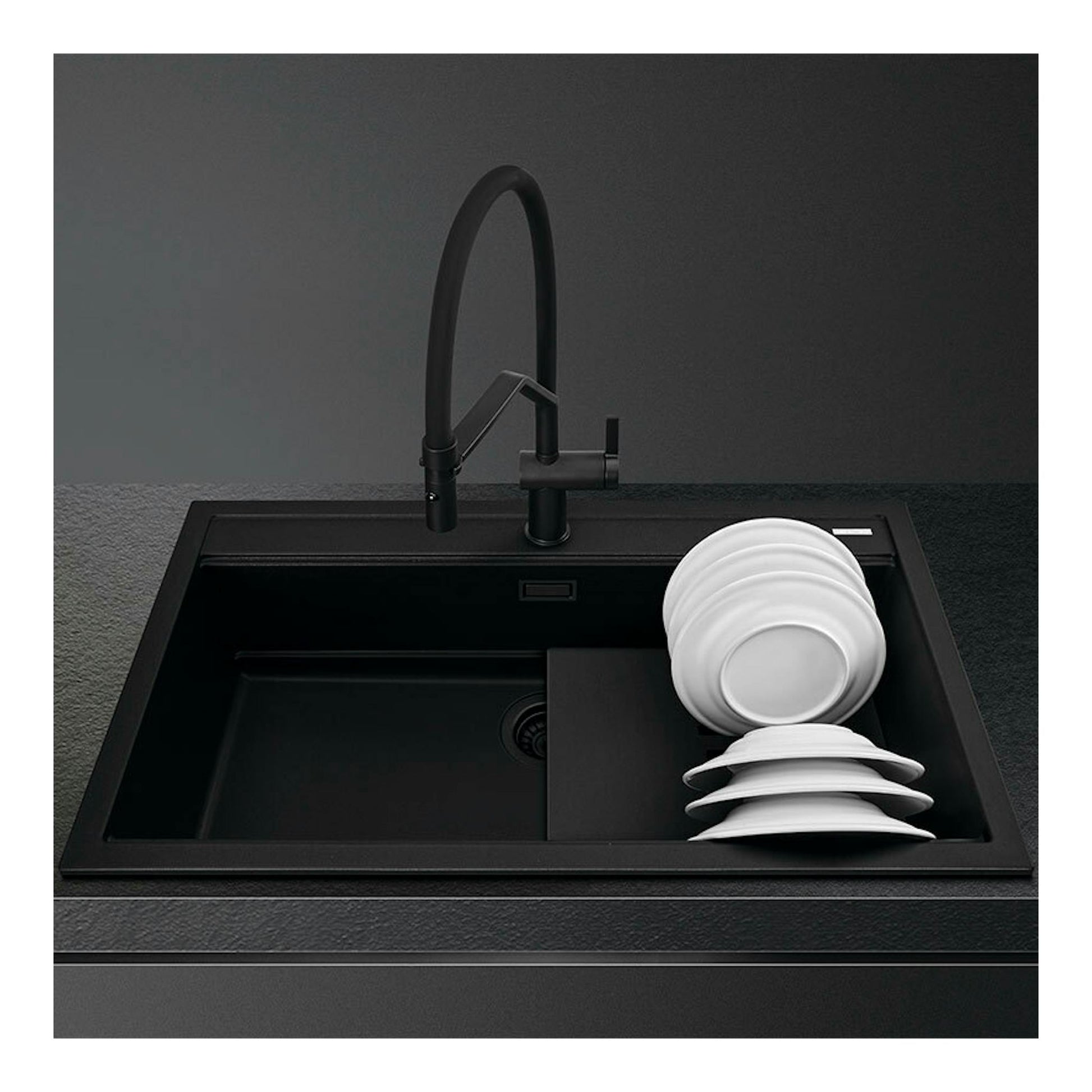 Fregadero Smeg VSGX860MN negro, vista frontal, con grifo negro y platos blancos apilados.