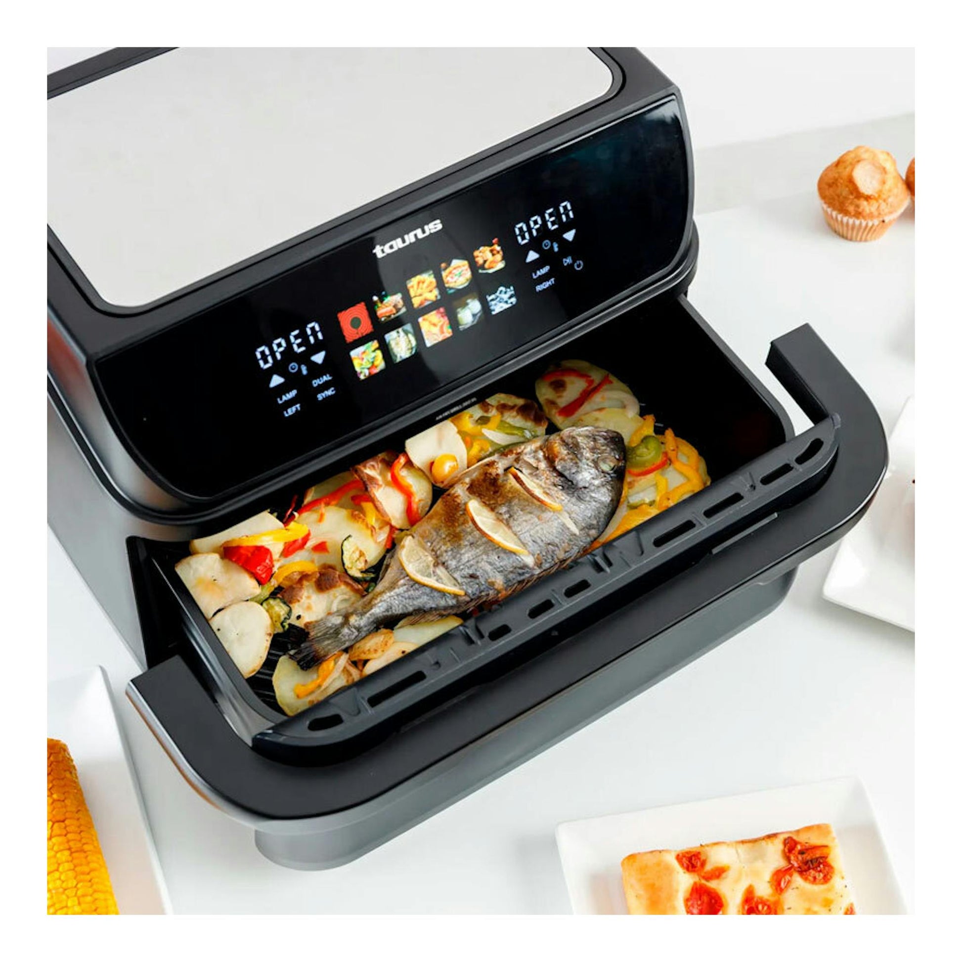 Freidora de aire Taurus Grill 360 negra y gris, vista frontal inclinada, con cesta abierta y comida dentro.