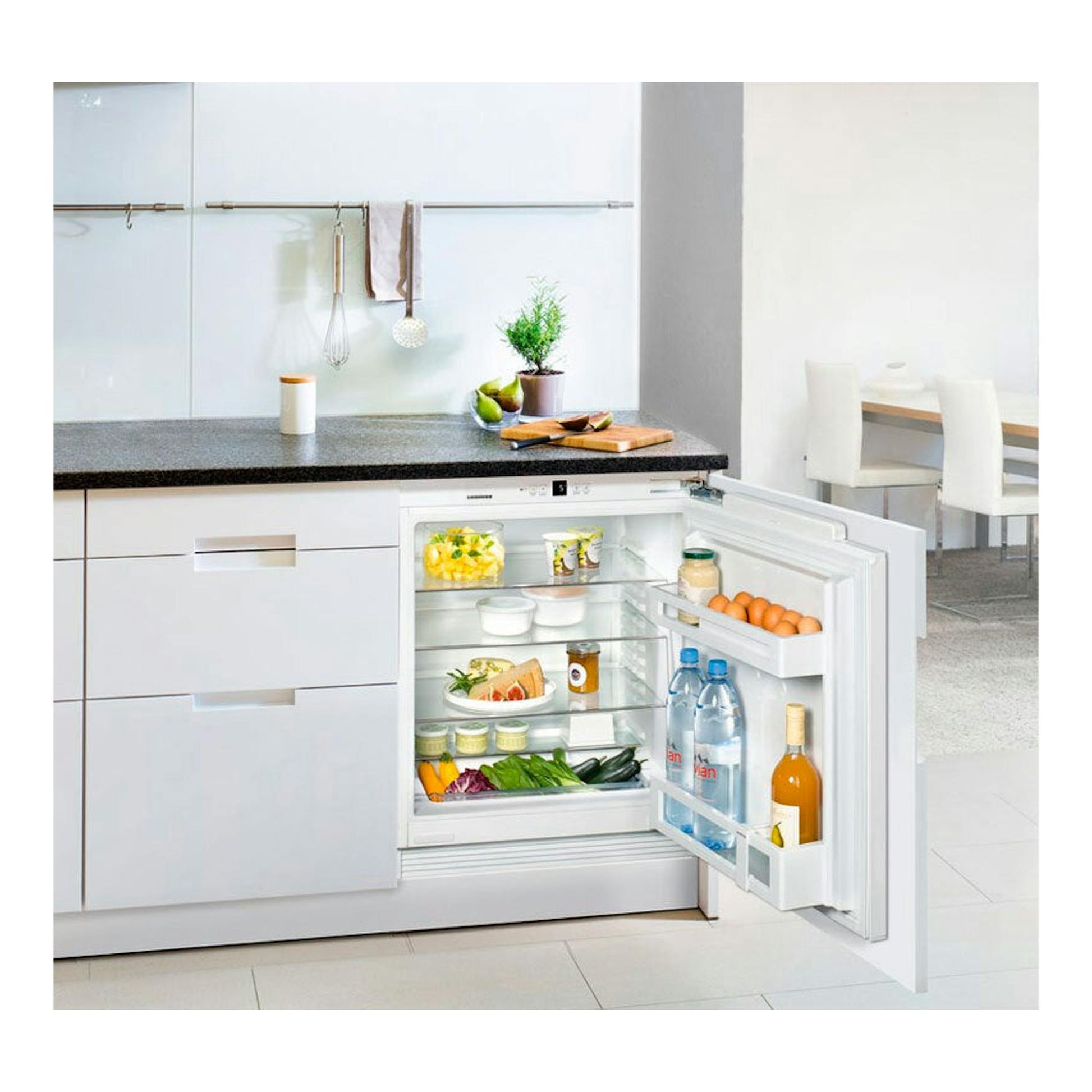 Frigorífico integrable Liebherr UIK 1510 abierto de frente en cocina blanca, con estantes y alimentos.