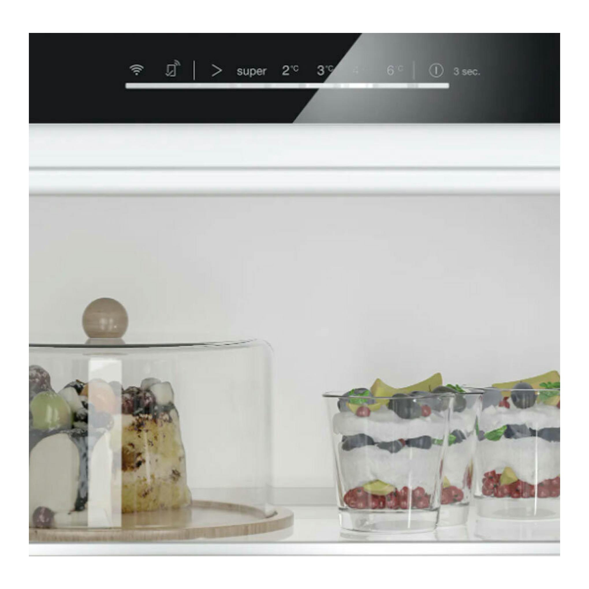 Vista interior de frigorífico Siemens KU21RADE0, con estante blanco y postres en recipientes de cristal.