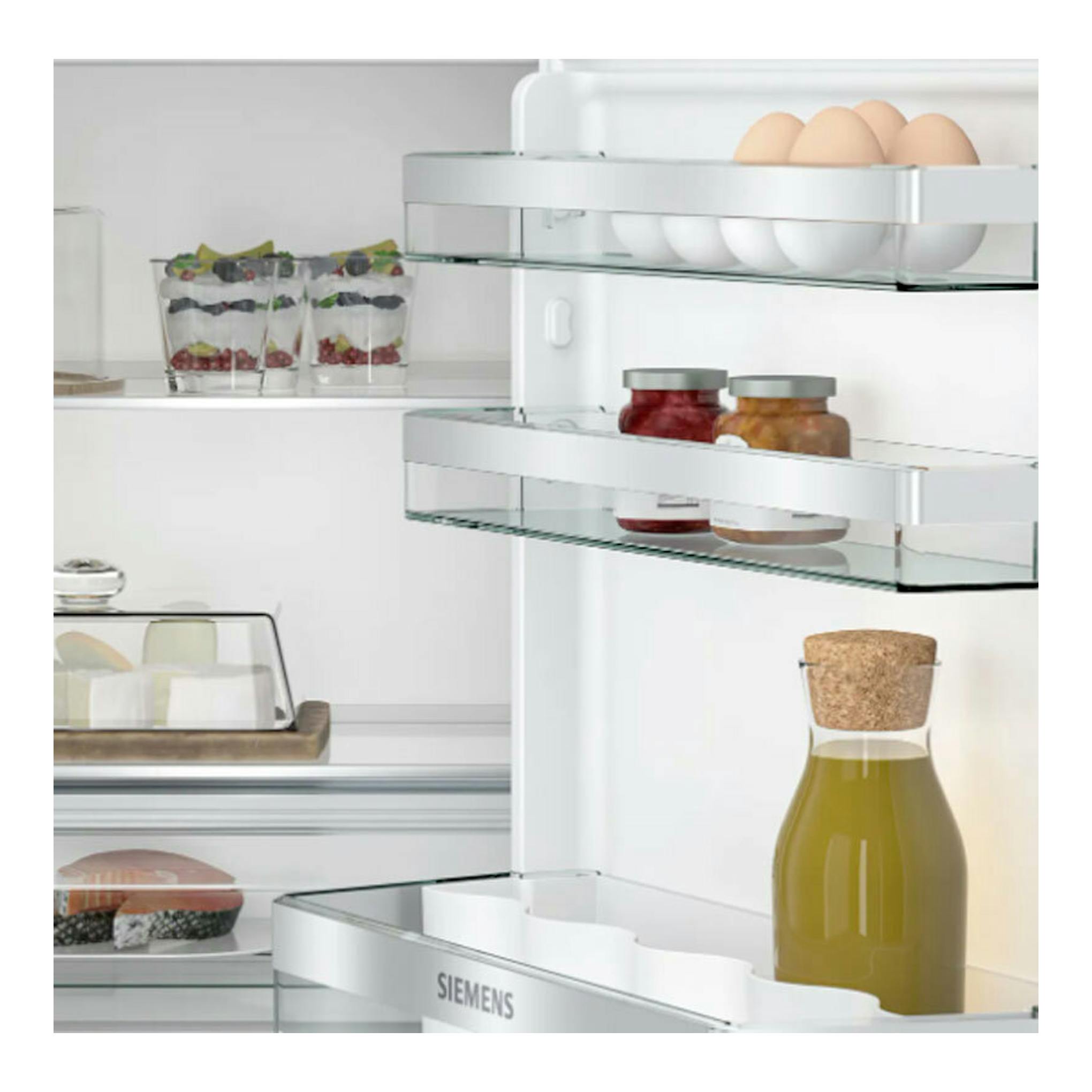 Frigorífico integrable Siemens KU21RADE0, vista interior frontal con estantes de cristal y alimentos.