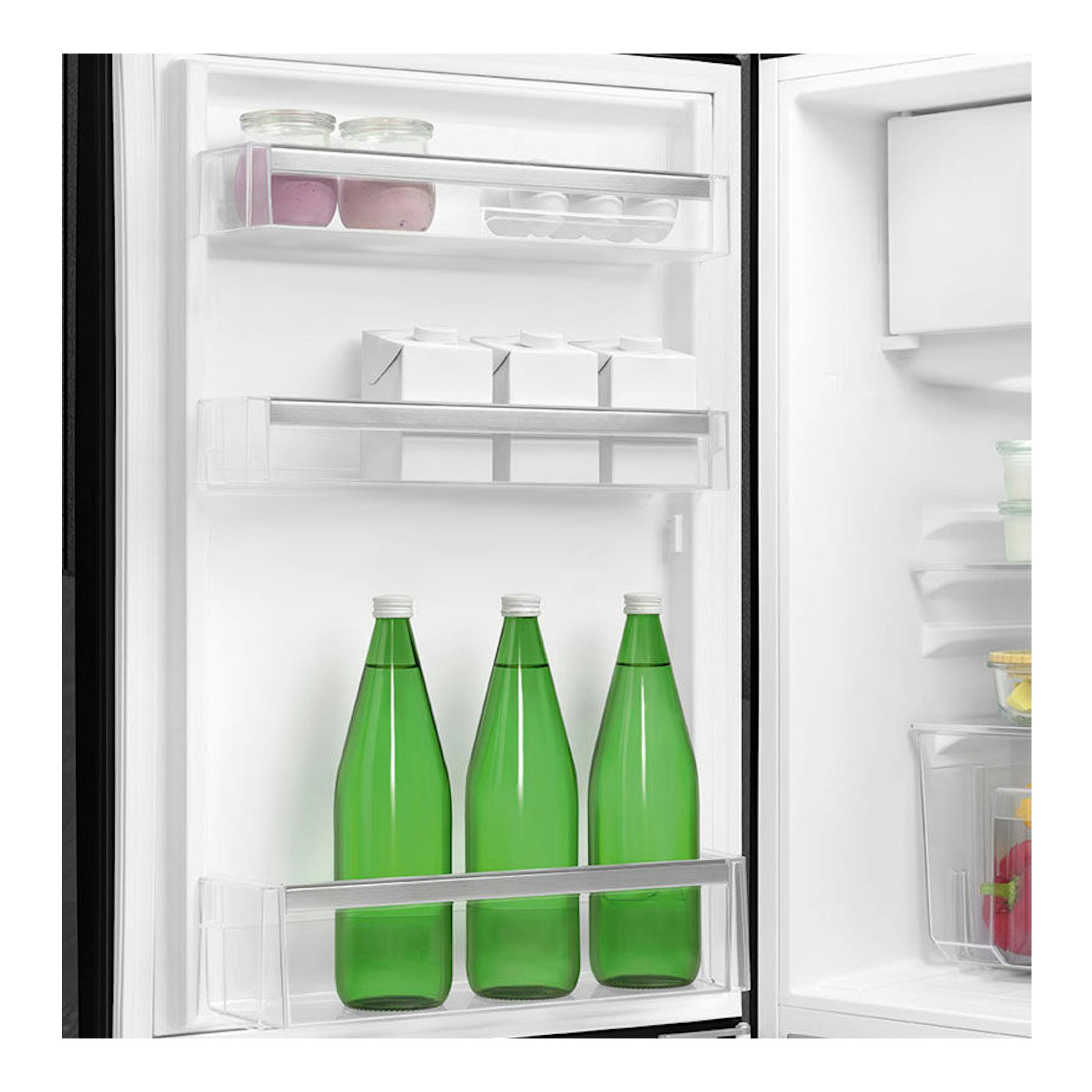Interior de frigorífico Smeg FAB10LBL5 negro, con baldas en la puerta y tres botellas verdes.