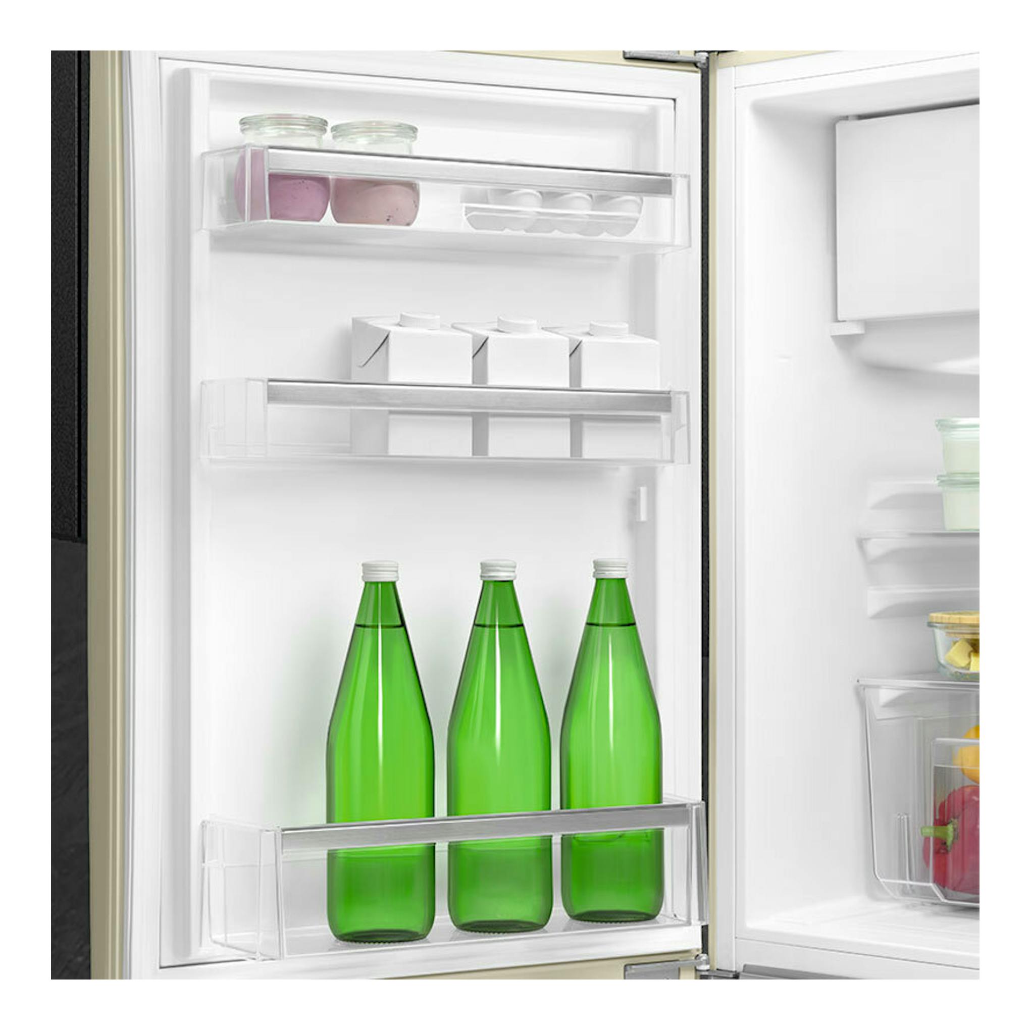 Interior de frigorífico Smeg FAB10LCR6 crema, con la puerta abierta, estantes y tres botellas verdes.