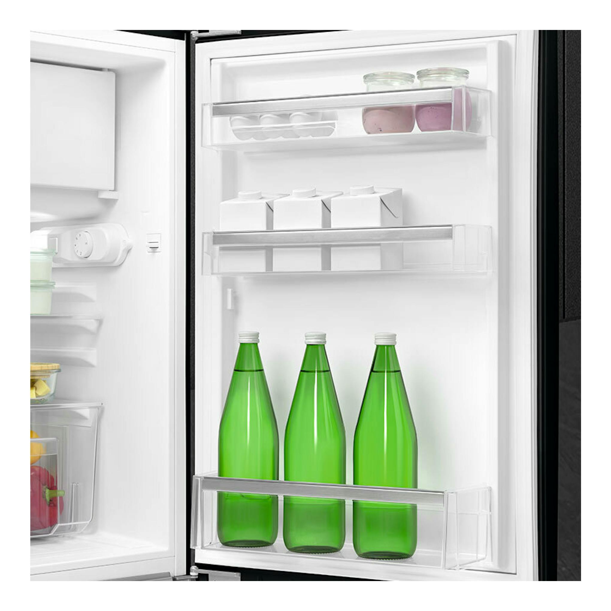 Vista frontal del interior de frigorífico Smeg FAB10RBL6 negro, con botellas verdes y tarros en estantes blancos.