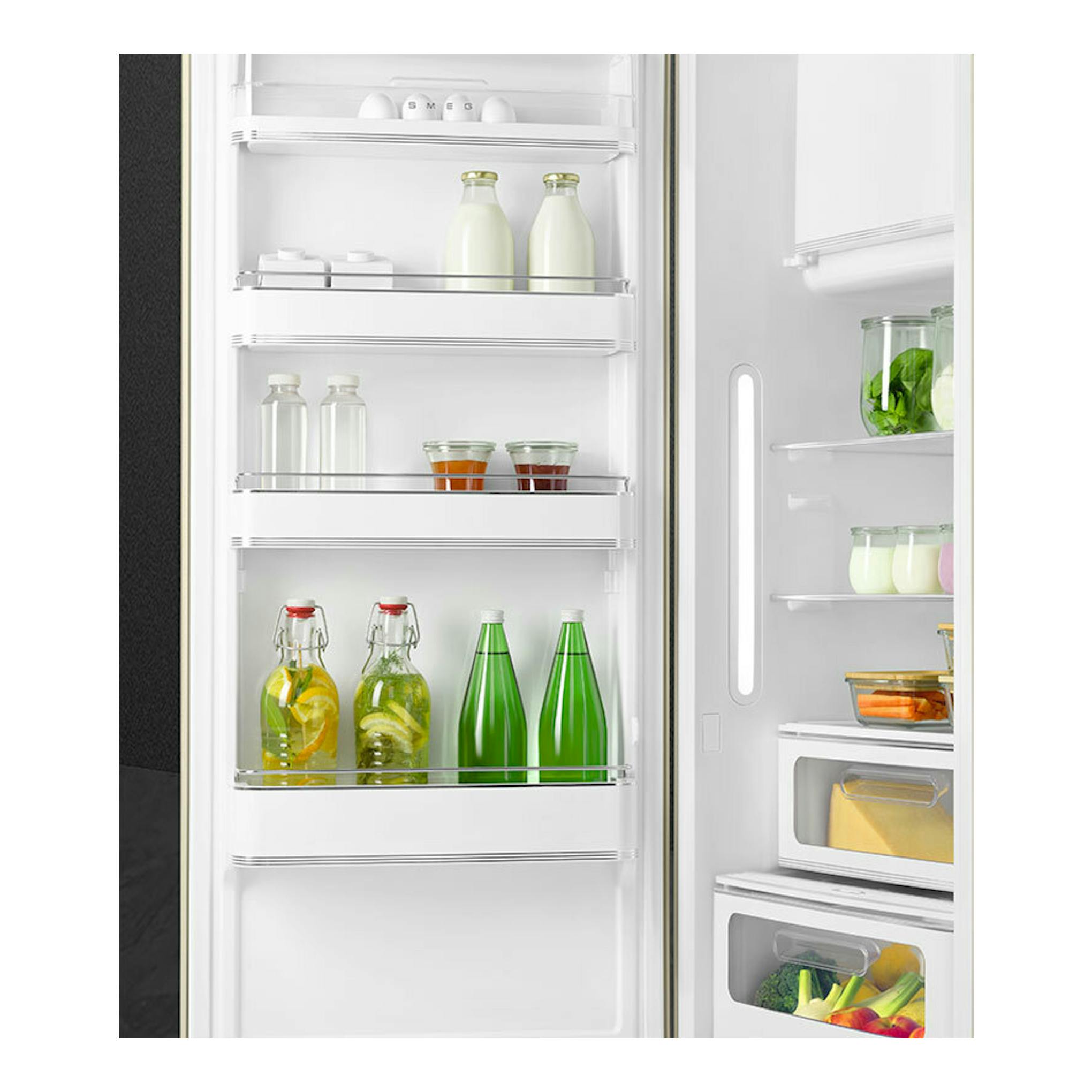 Vista frontal del interior de un frigorífico Smeg FAB28LCR6 crema, con estantes blancos, botellas y tarros.