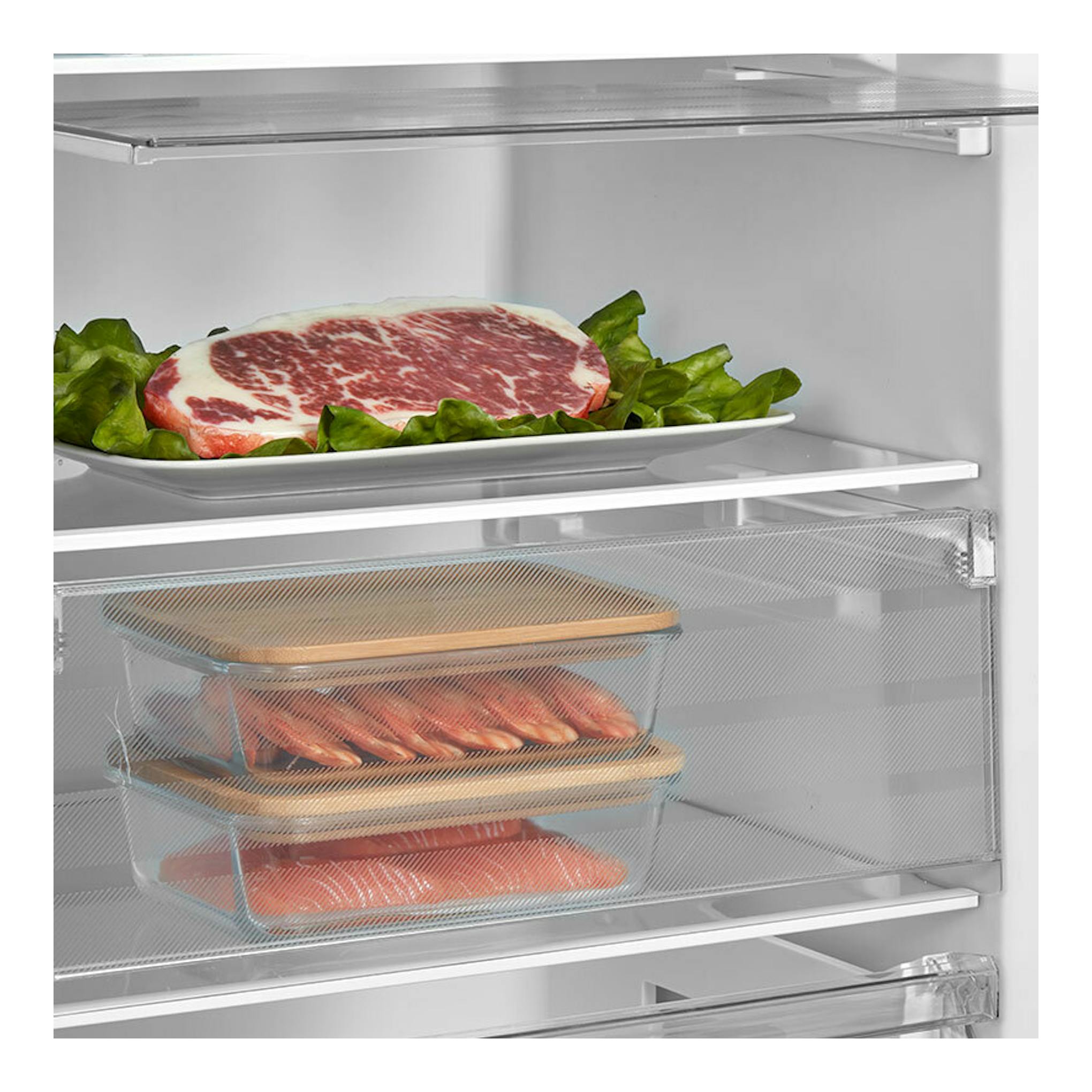 Vista interior frontal de frigorífico Teka RSL75640SS inox, con carne en bandeja y cajones transparentes.